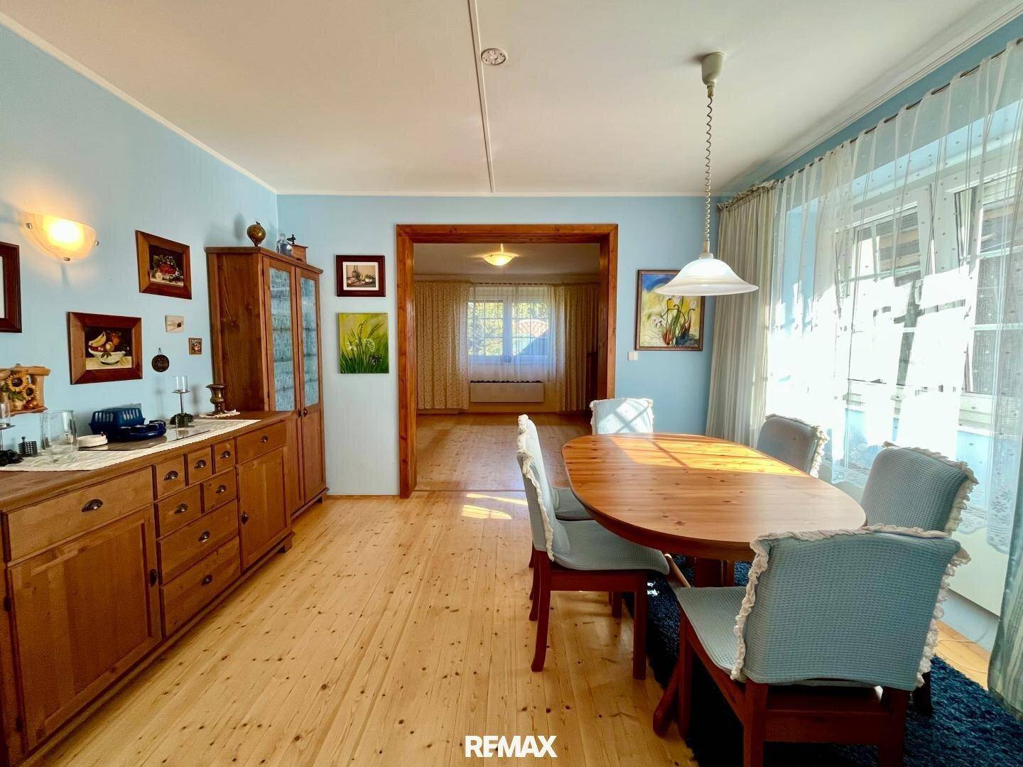 Helles Esszimmer mit Holzboden, traditionellen Möbeln und Zugang zu einem weiteren Raum.