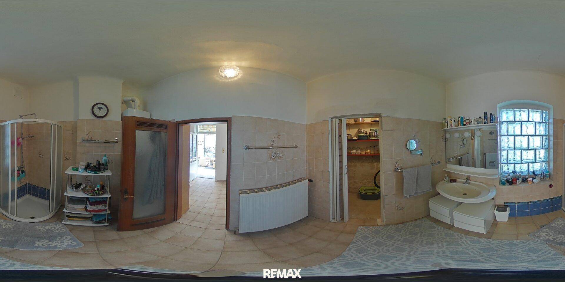 Geräumiges Badezimmer mit Dusche, Waschbecken und Fliesenboden in neutralen Farbtönen.