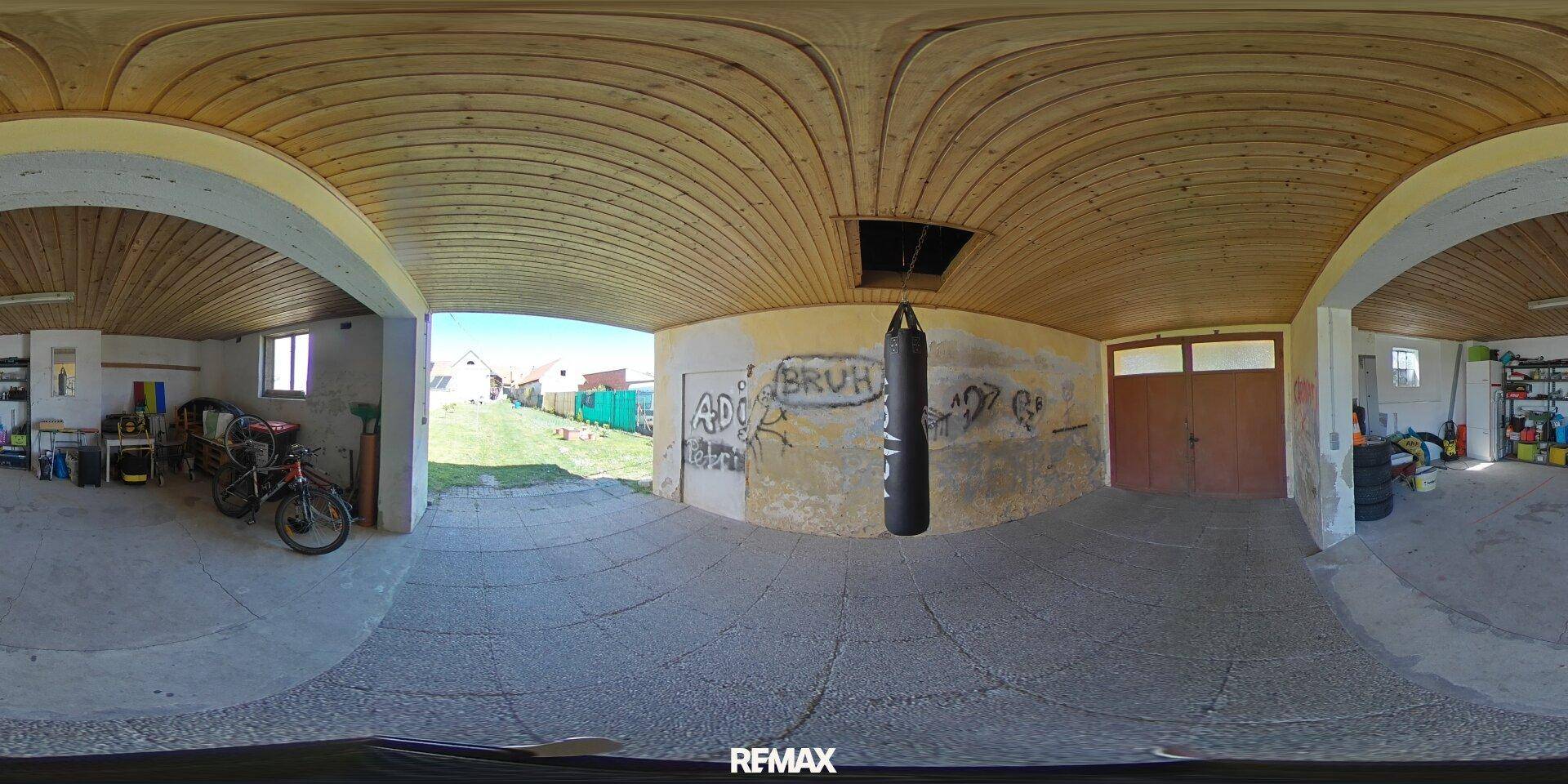 Großer Garagenbereich mit Holzbalkendecke, Boxsack und Zugang zum Garten.
