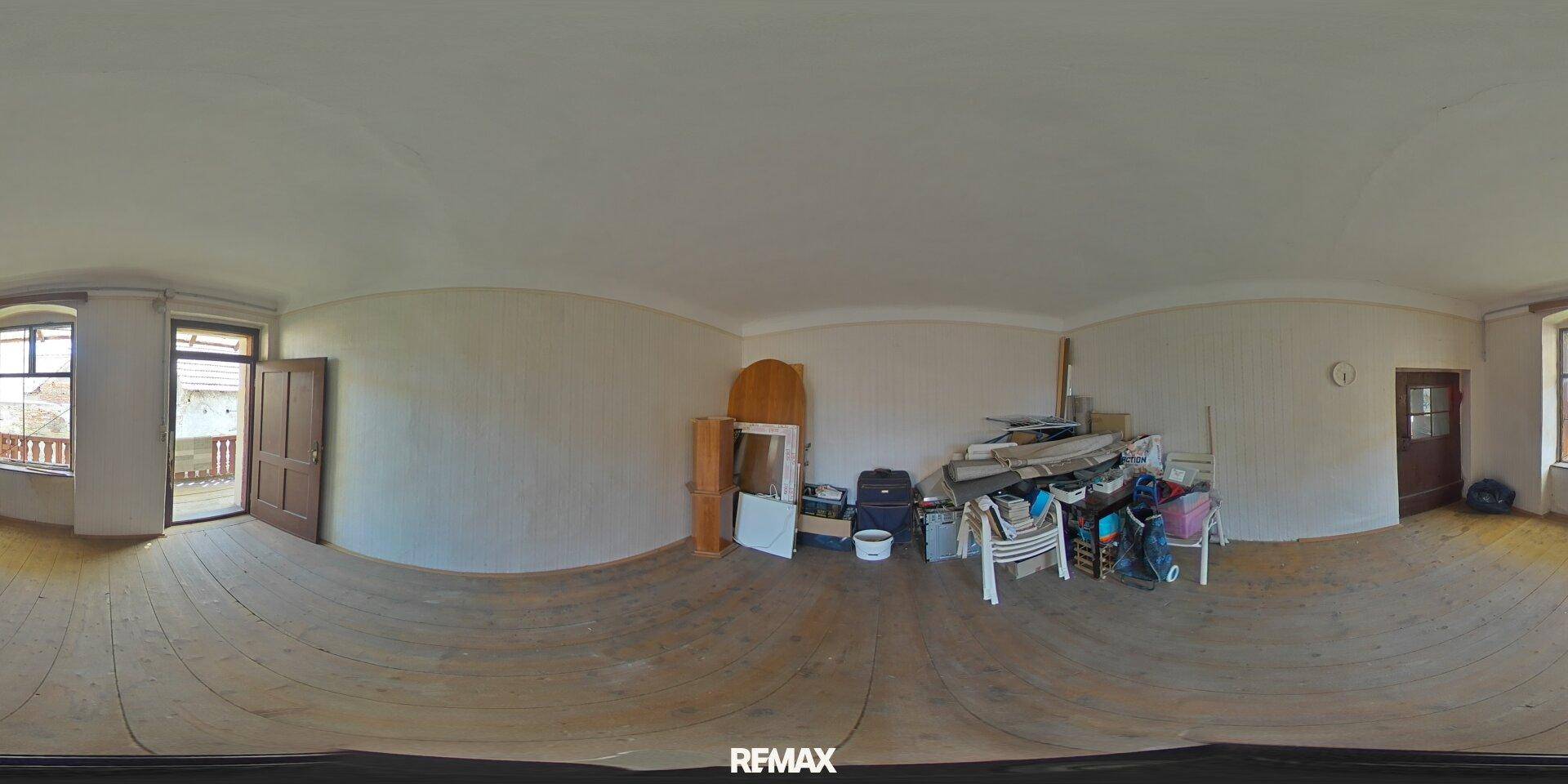Geräumiger Raum mit Holzdielenboden und Zugang zu einem Balkon, bereit zur Renovierung.
