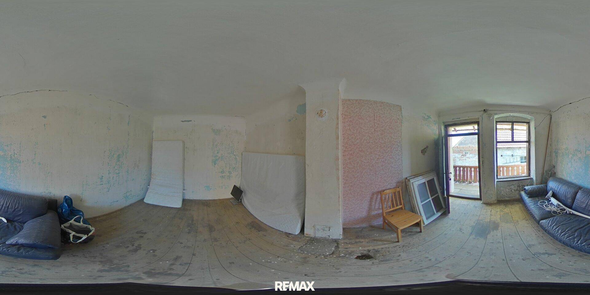 Großer Wohnraum mit Holzdielenboden und Balkonzugang, der eine Renovierung benötigt.