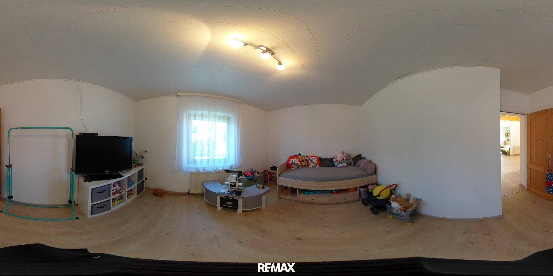 Helles Schlafzimmer oder Kinderzimmer mit Bett, Fernseher und einem Fenster, das viel Licht hereinlässt.