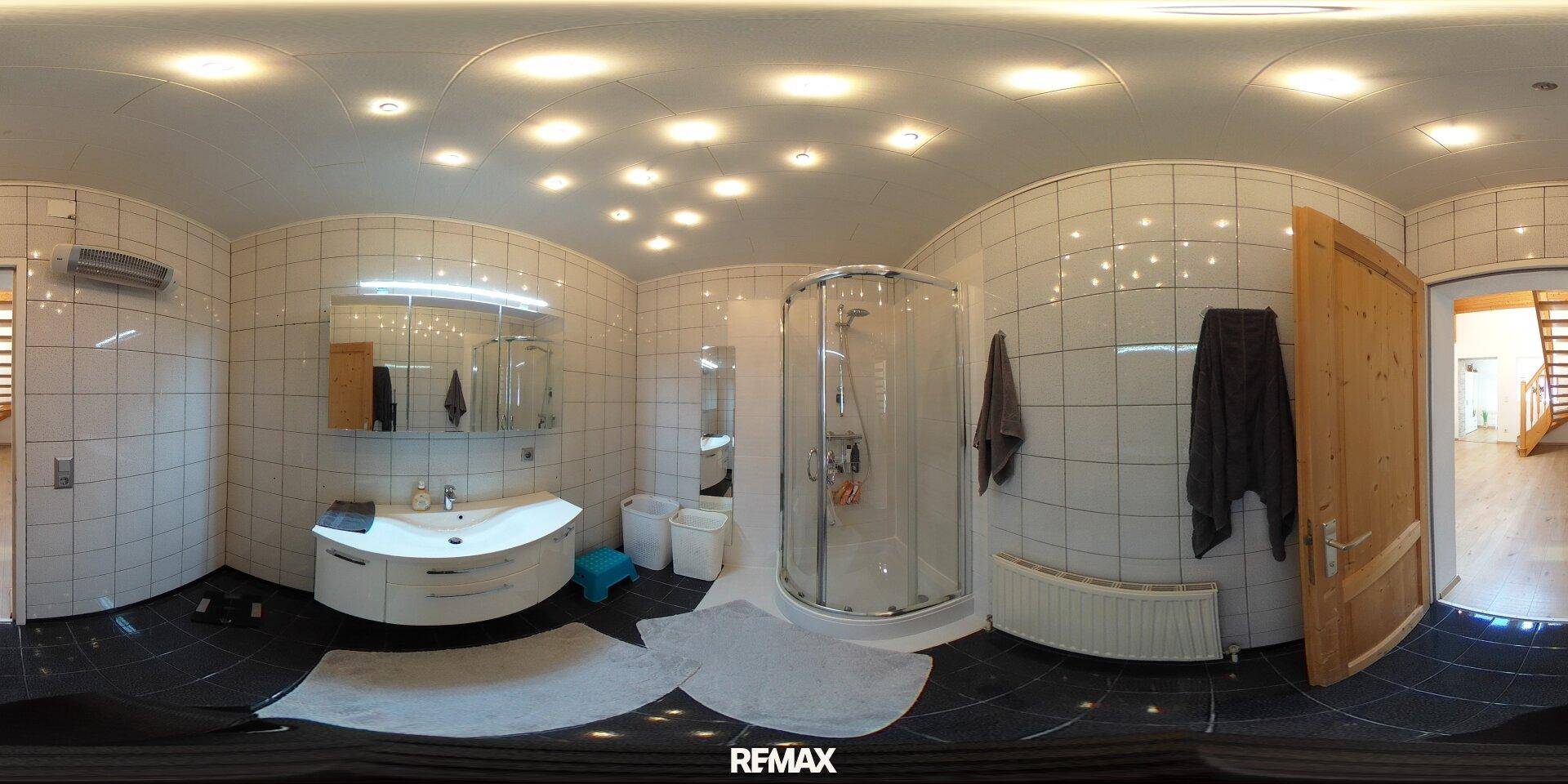 Modernes Badezimmer mit weißen Wandfliesen, schwarzen Bodenfliesen und einer geräumigen Duschkabine.