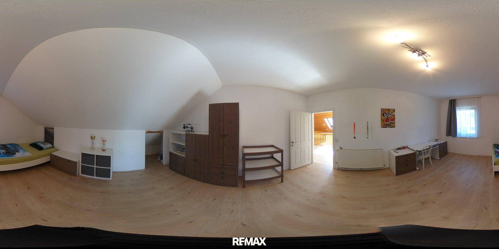 Dachzimmer mit schrägen Decken, einem Bett und praktischen Aufbewahrungsmöbeln, ideal als Schlafzimmer.