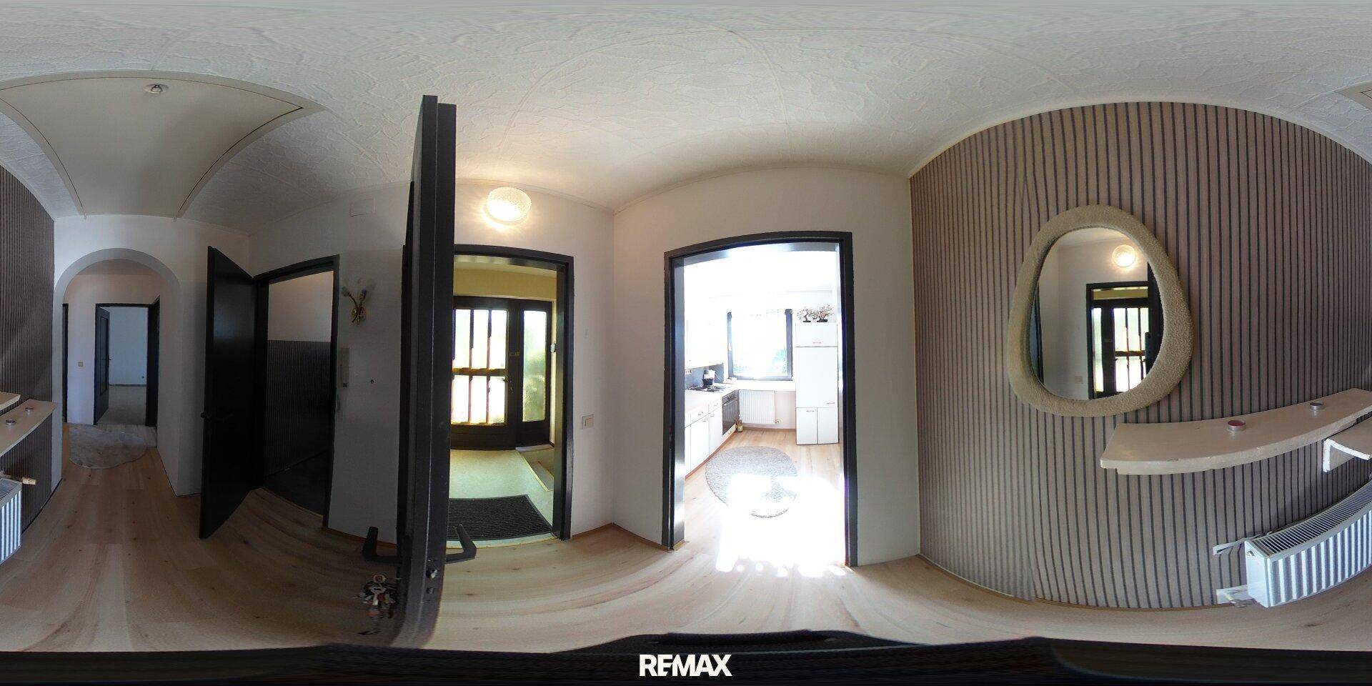 Panoramablick auf einen Flur mit Holzboden, dekorativer Wand und Zugang zur Küche.