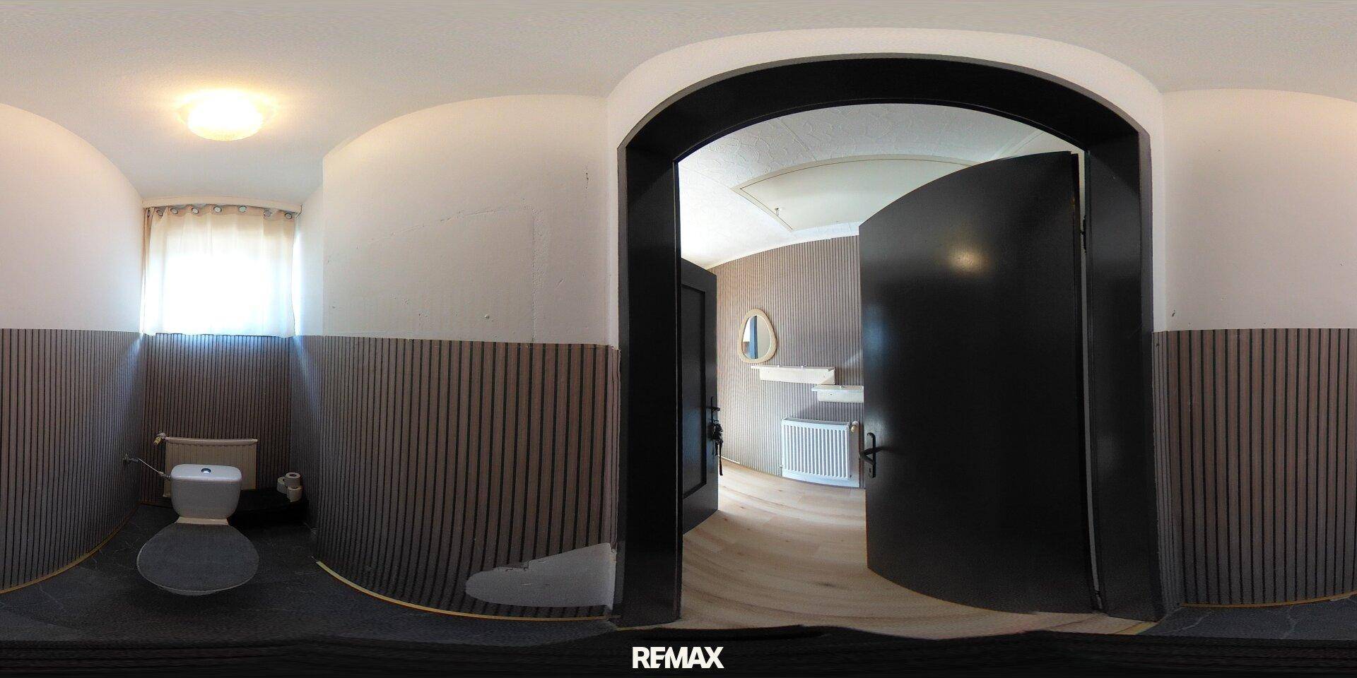 Panoramablick auf ein kleines WC mit Fenster und einfacher Ausstattung.