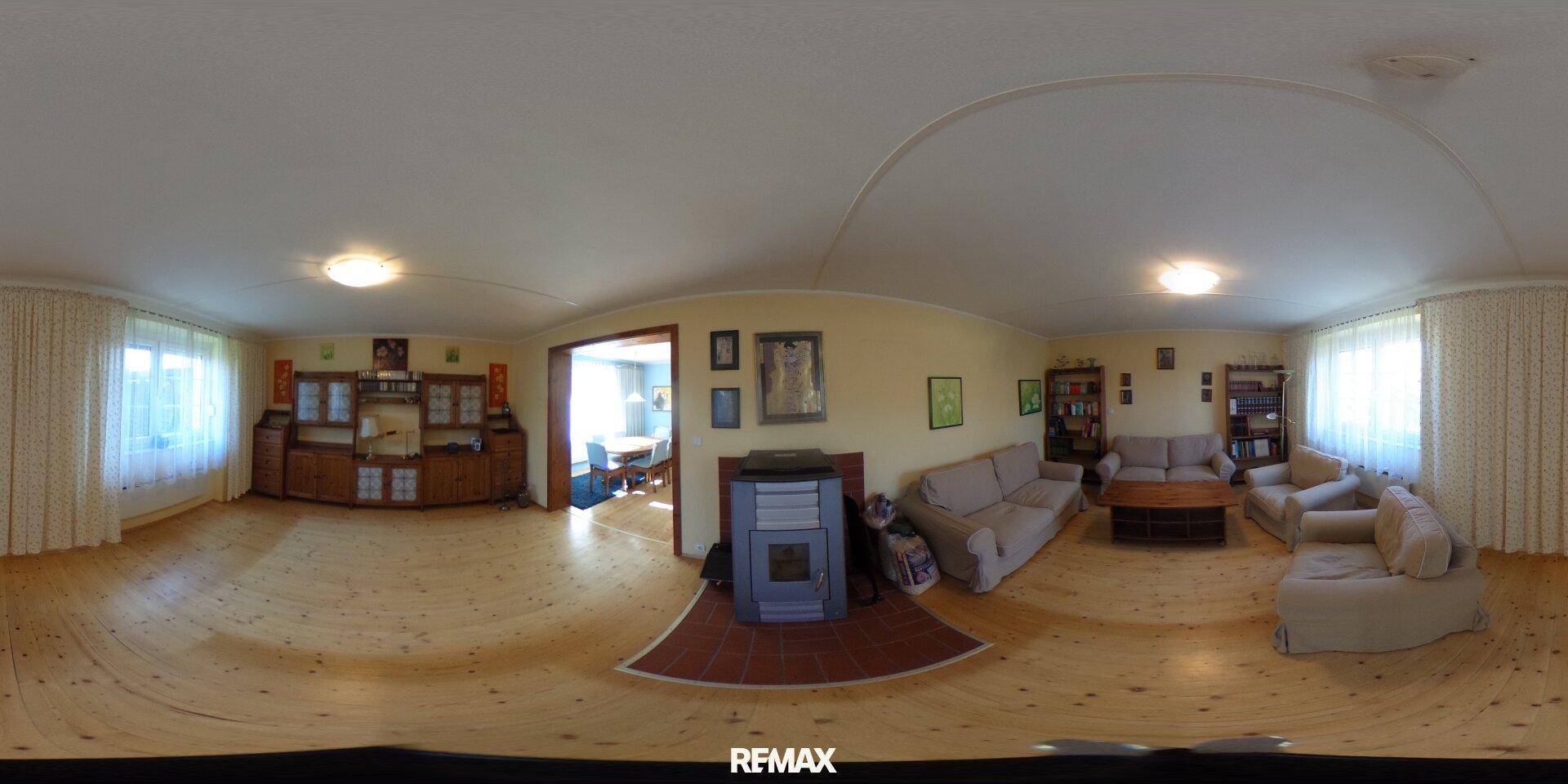 Gemütliches Wohnzimmer mit Holzboden, bequemen Sofas und Kaminofen.