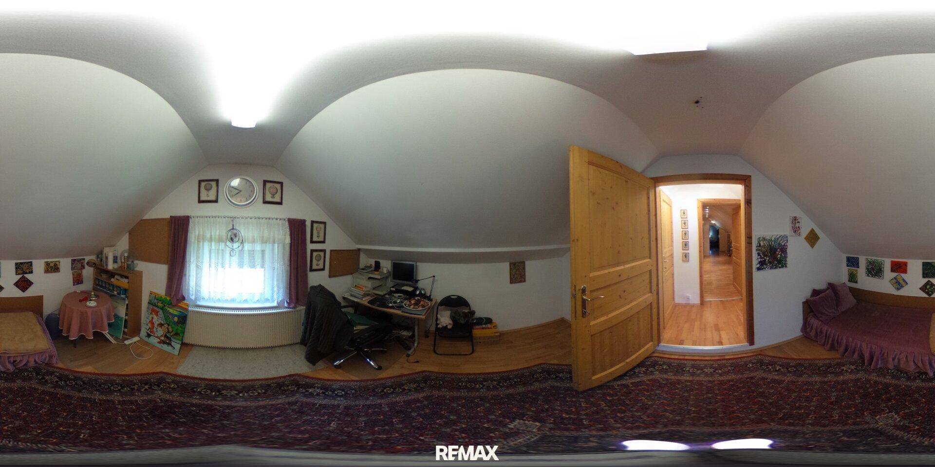 Dachgeschosszimmer als Büro eingerichtet mit Schreibtisch, Stuhl und Fenster für Tageslicht.