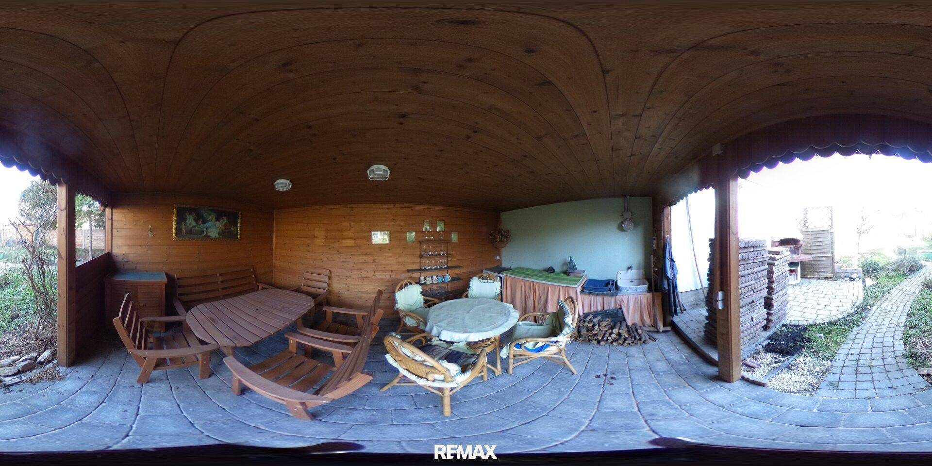 Überdachte Terrasse mit Holzboden und Gartenmöbeln, ideal für Mahlzeiten im Freien.