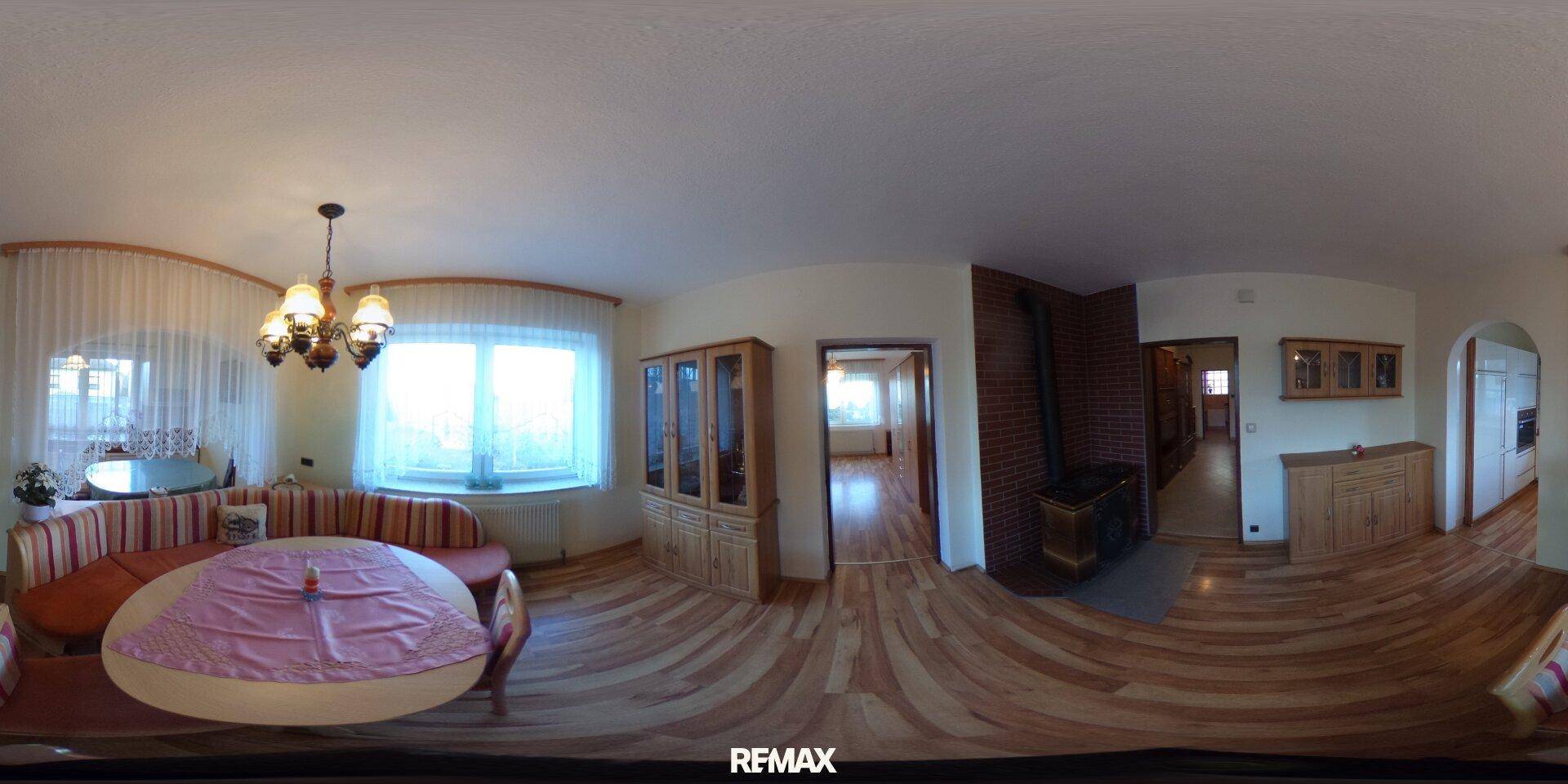 Gemütliches Wohnzimmer mit Holzboden, Kaminofen und großem Fenster, eingerichtet mit bequemen Sofas.