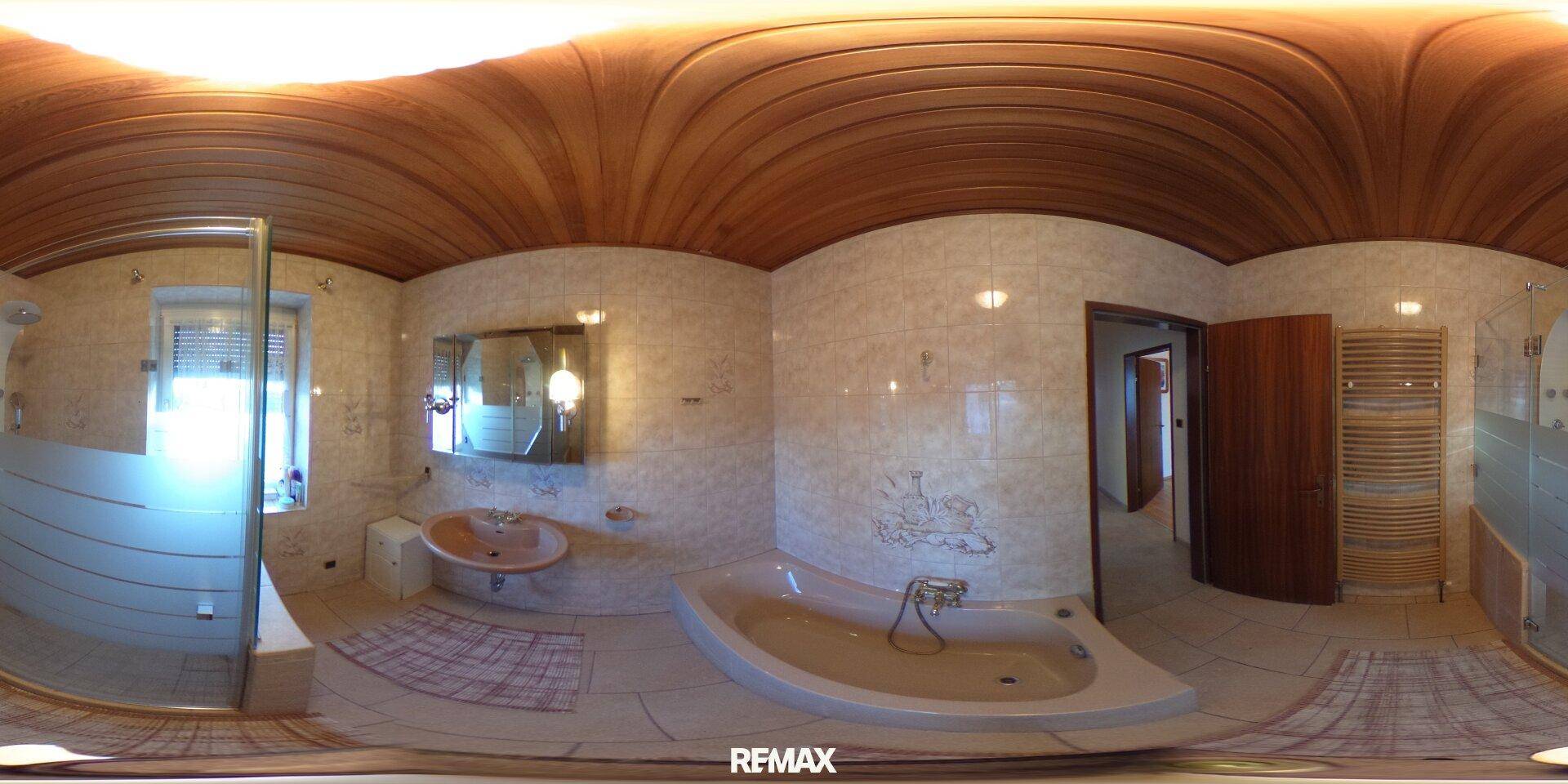 Panoramaansicht eines gefliesten Badezimmers mit Badewanne, Dusche und Holzdecke.