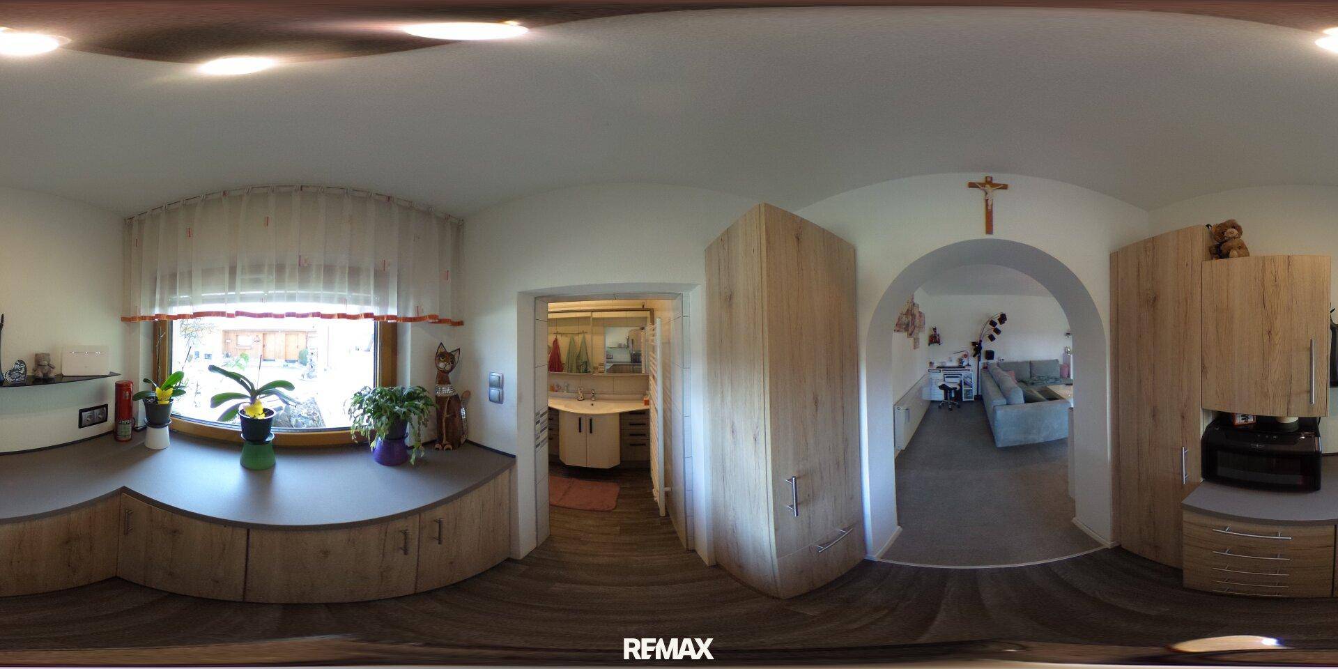Heller Flur mit Einbauschrank aus Holz, Fenster und einem Bogen, der zu einem weiteren Raum führt.