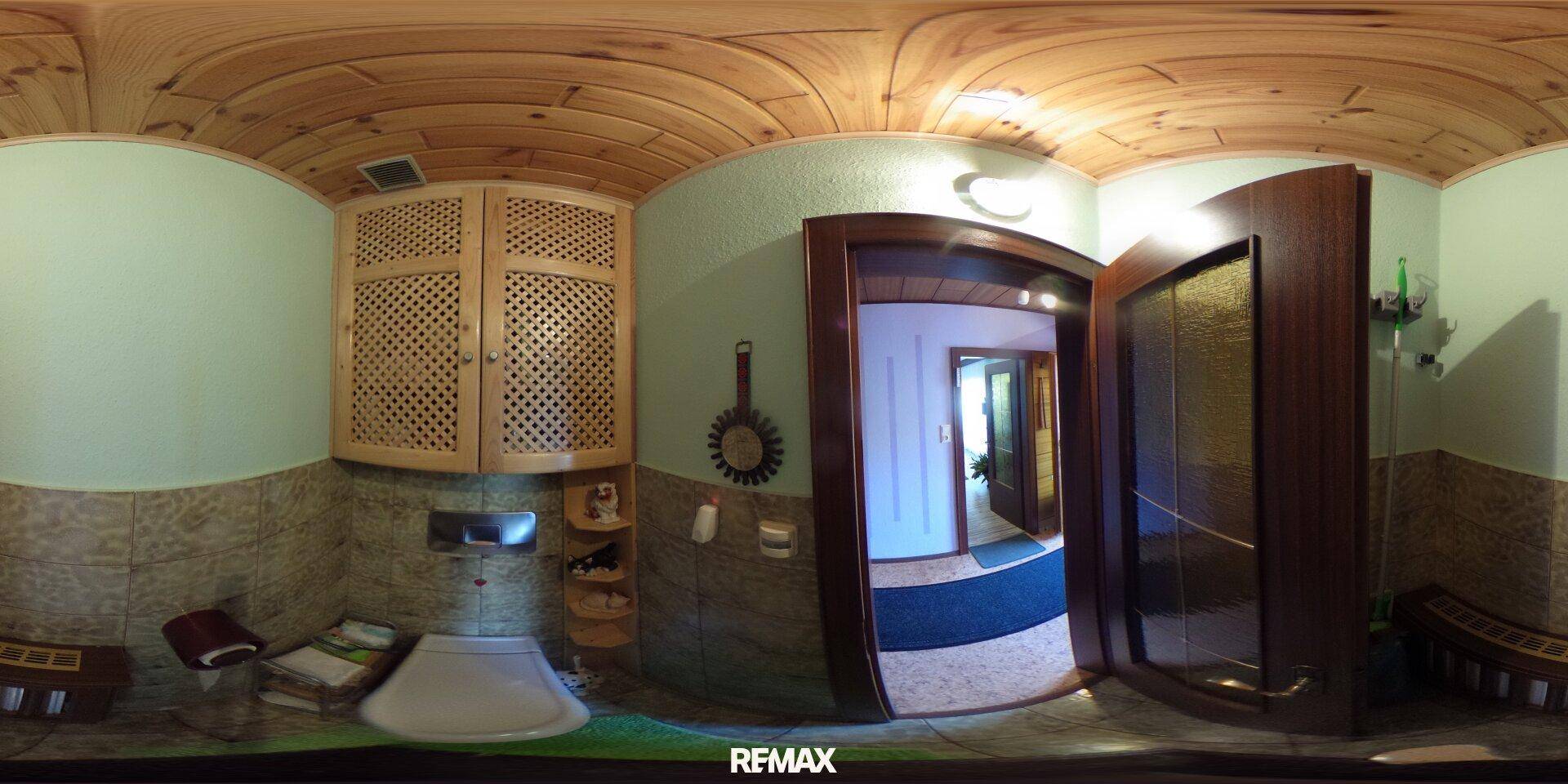 Kleines Gäste-WC mit Waschbecken, Holzschränken und gefliesten Wänden, praktisch und funktional.