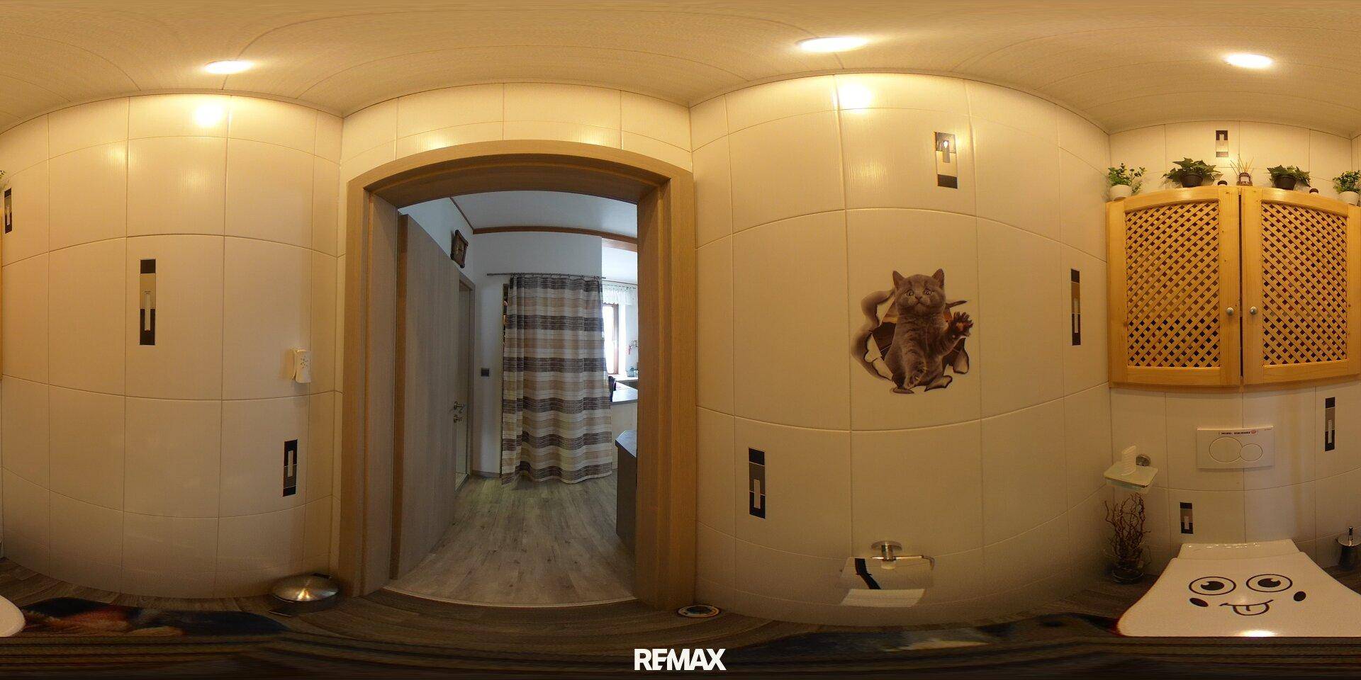 Helles Gäste-WC mit weißen Fliesen, Toilette und kleinem Holzschrank, sauber und gepflegt.