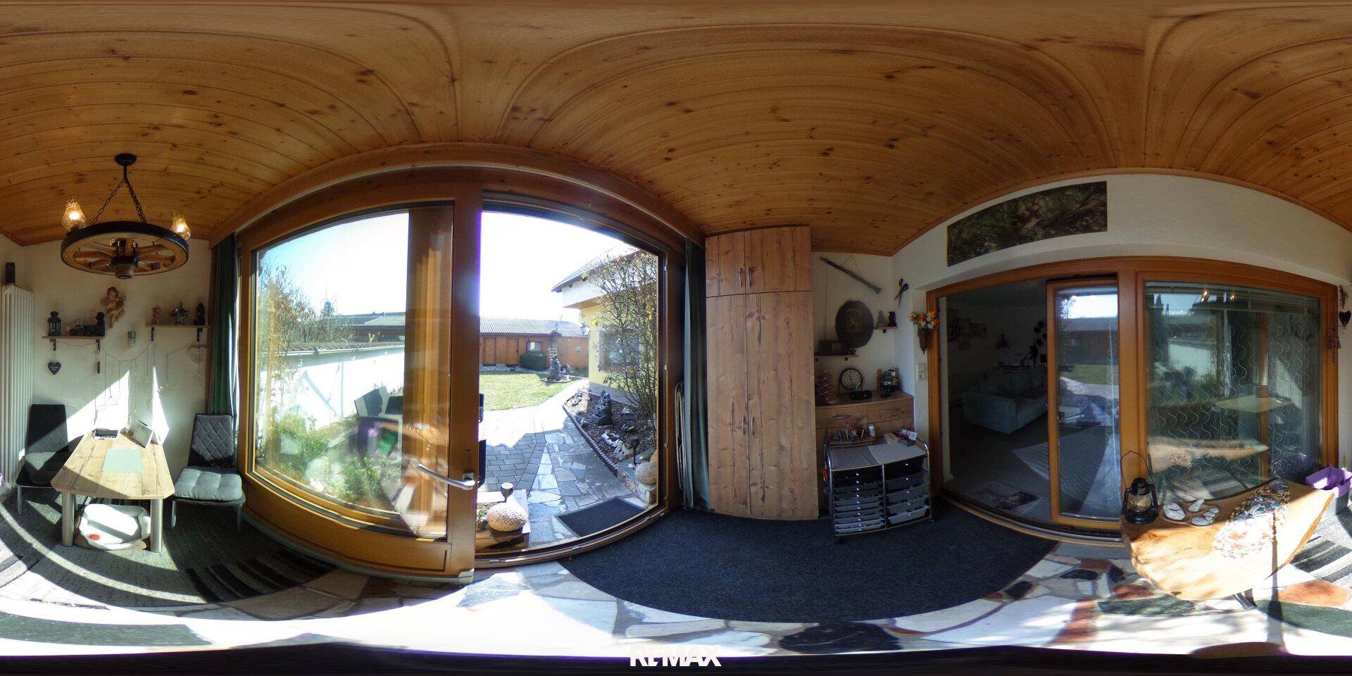 Helles Wohnzimmer mit großen Fenstern, Holzbalkendecke und kleinem Essbereich, bietet Zugang zum Garten.