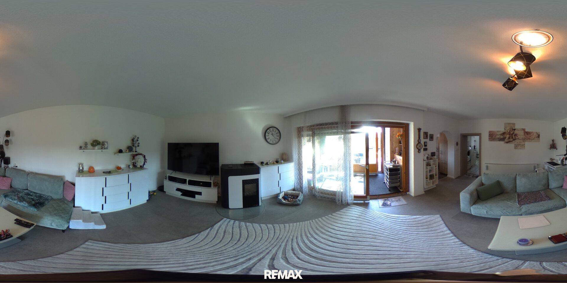 Modernes Wohnzimmer mit hellgrauen Wänden, Sofa, Fernseher und einem gemütlichen Holzofen.