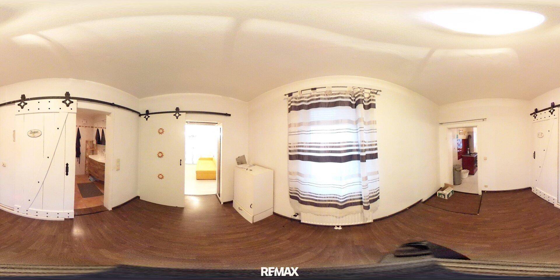 Panoramaaufnahme eines Flurs mit dunklem Holzfußboden und weißen Schiebetüren.