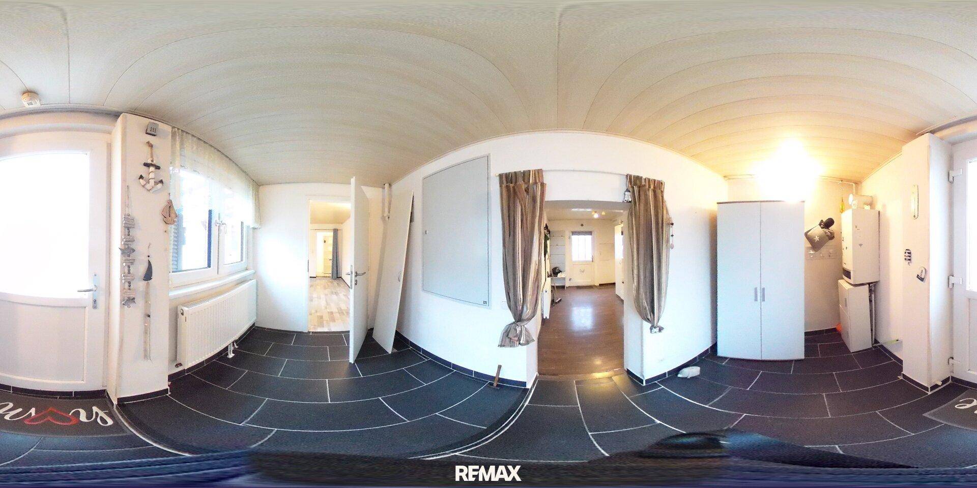 Panoramaaufnahme eines Hauswirtschaftsraums mit dunklen Fliesen und Heizkörpern.