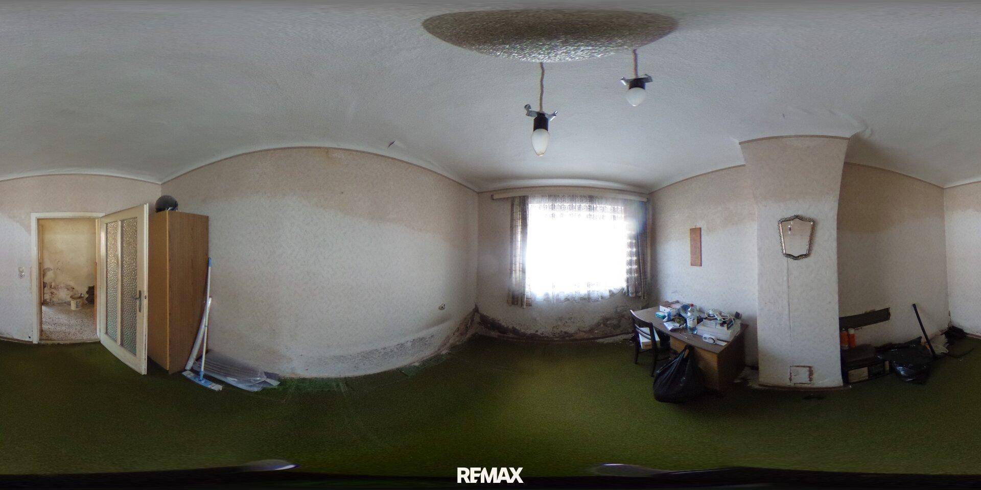 Schlafzimmer mit grünem Teppichboden und einem Fenster, das viel Tageslicht hereinlässt.