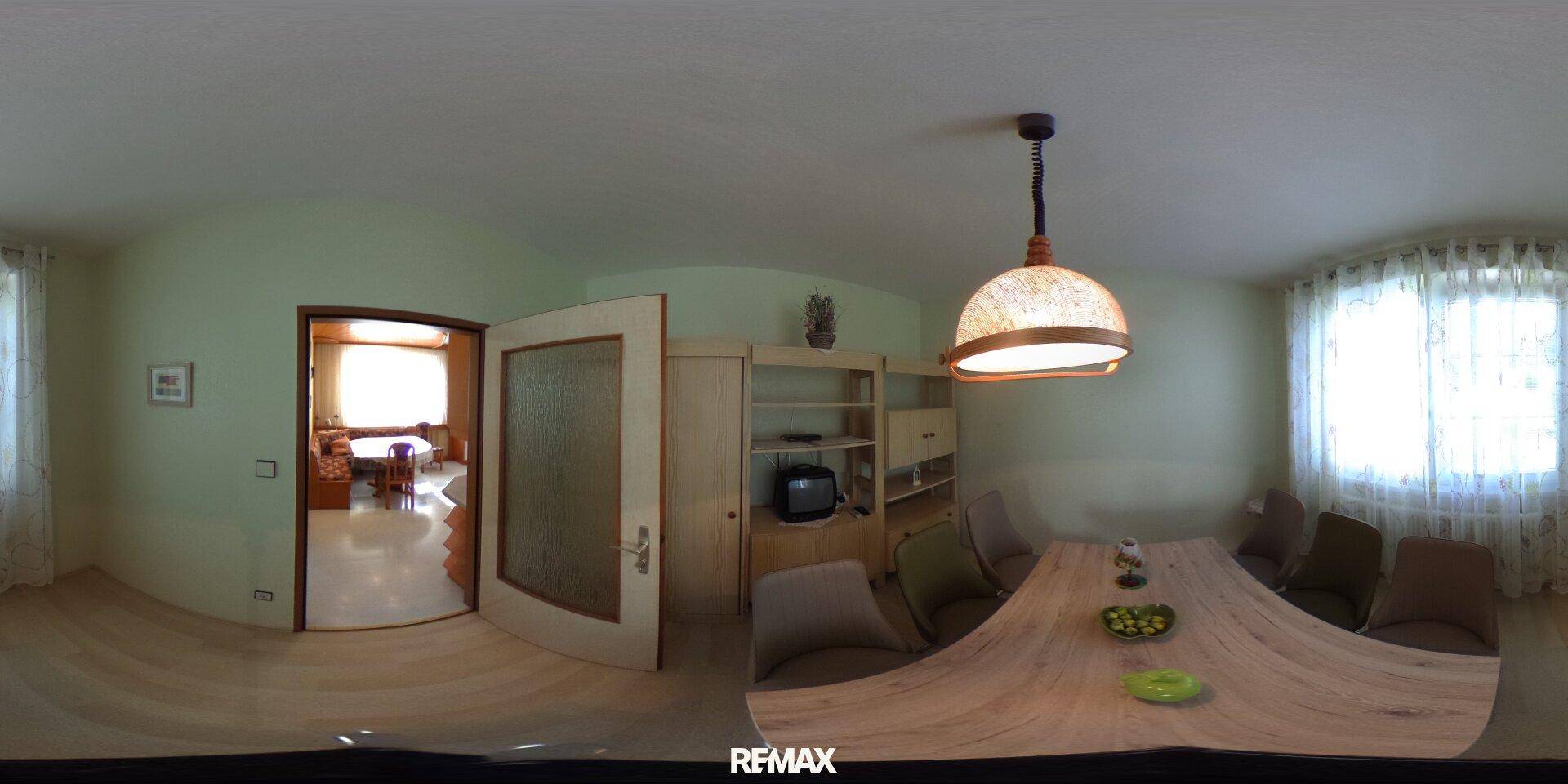 Heller Essbereich mit Holztisch, modernen Stühlen und Blick in einen weiteren Raum.