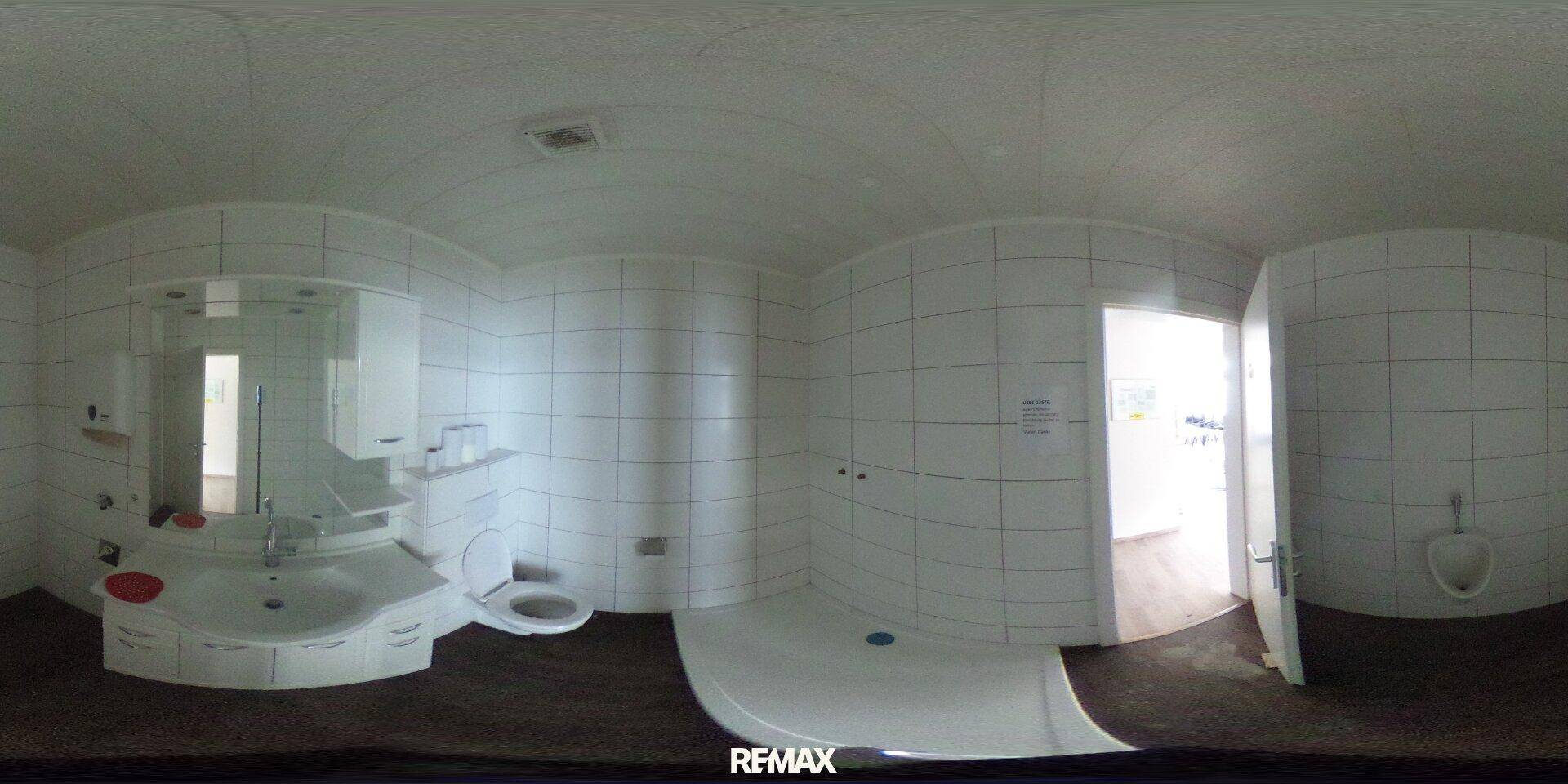 Helles Badezimmer mit weißen Fliesen, Waschbecken, Toilette und Urinal, in gutem Zustand.