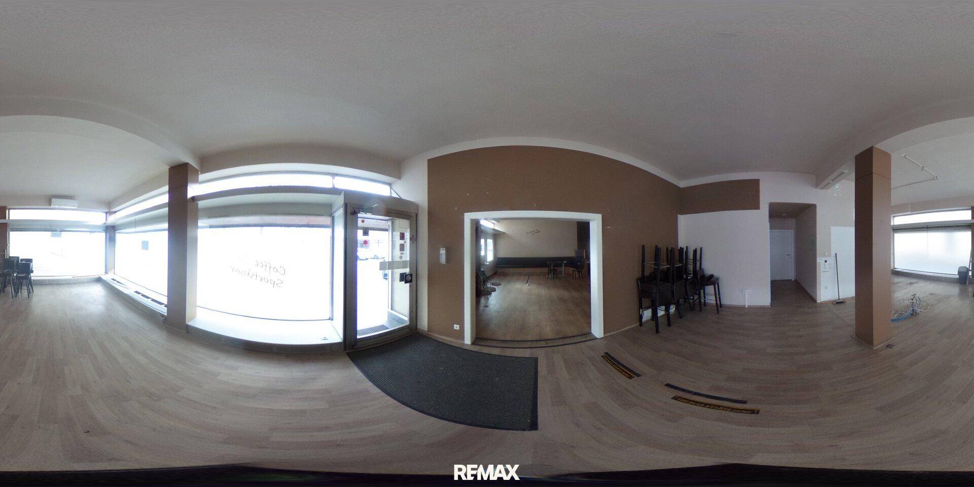 Panoramaansicht eines Gewerberaums mit Holzboden, breiter Fensterfront und Blick auf die Straße.