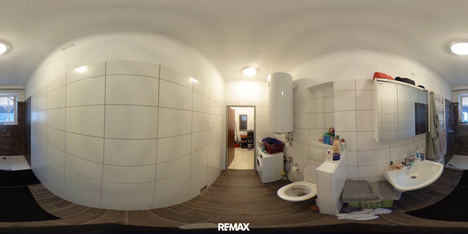 Helles Badezimmer mit weißen Fliesen, Toilette, Waschbecken und Waschmaschine, gut beleuchtet.