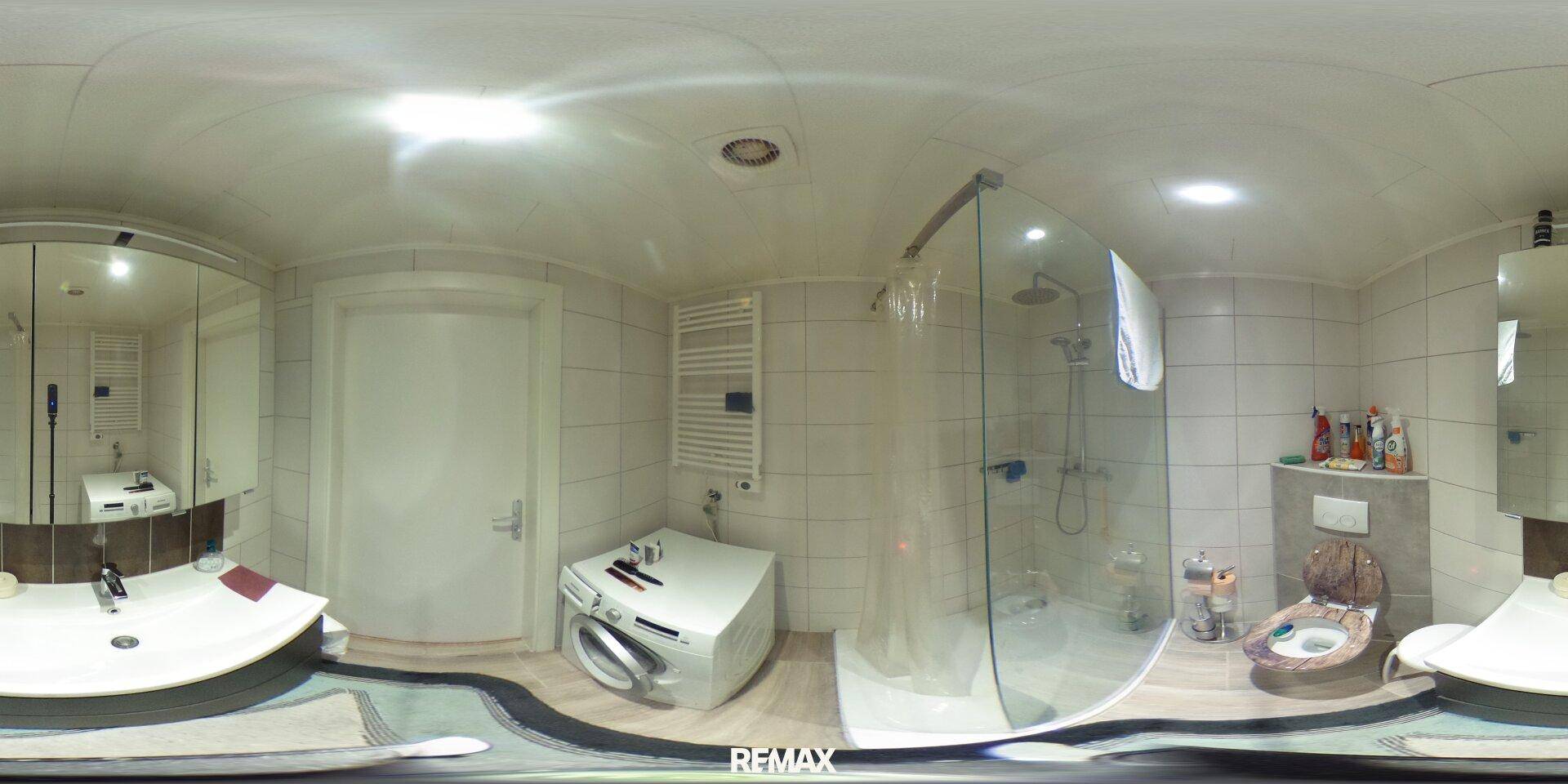 Modernes Badezimmer mit Duschkabine, Waschbecken, Toilette und Waschmaschine, hell gefliest.