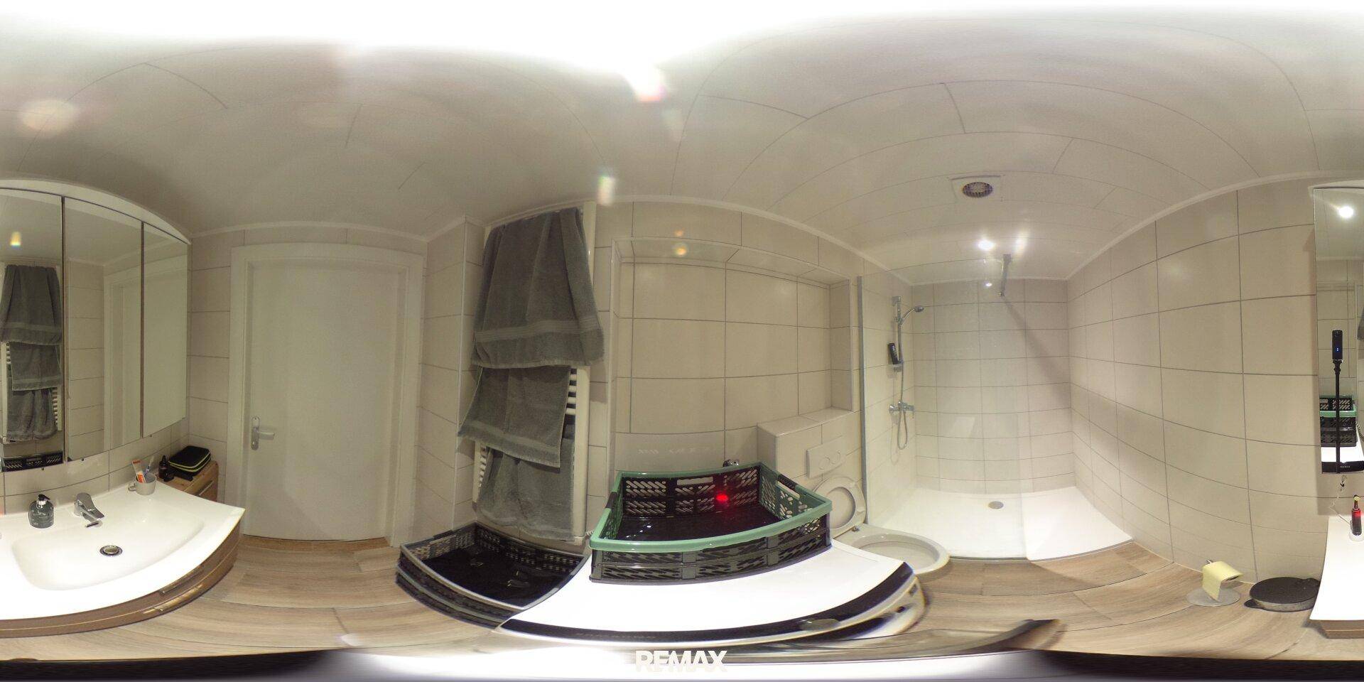 Helles Badezimmer mit Duschkabine, Waschbecken und Toilette, modern gefliest.