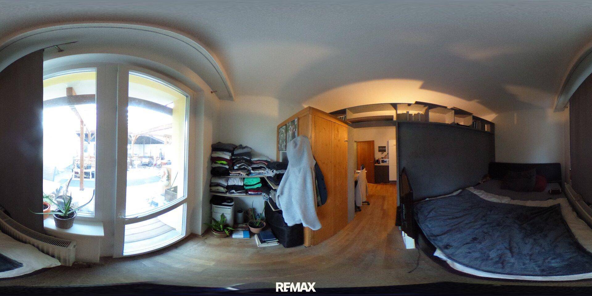 Schlafzimmer mit großem Fenster, Holzboden und Stauraum, bietet viel natürliches Licht.