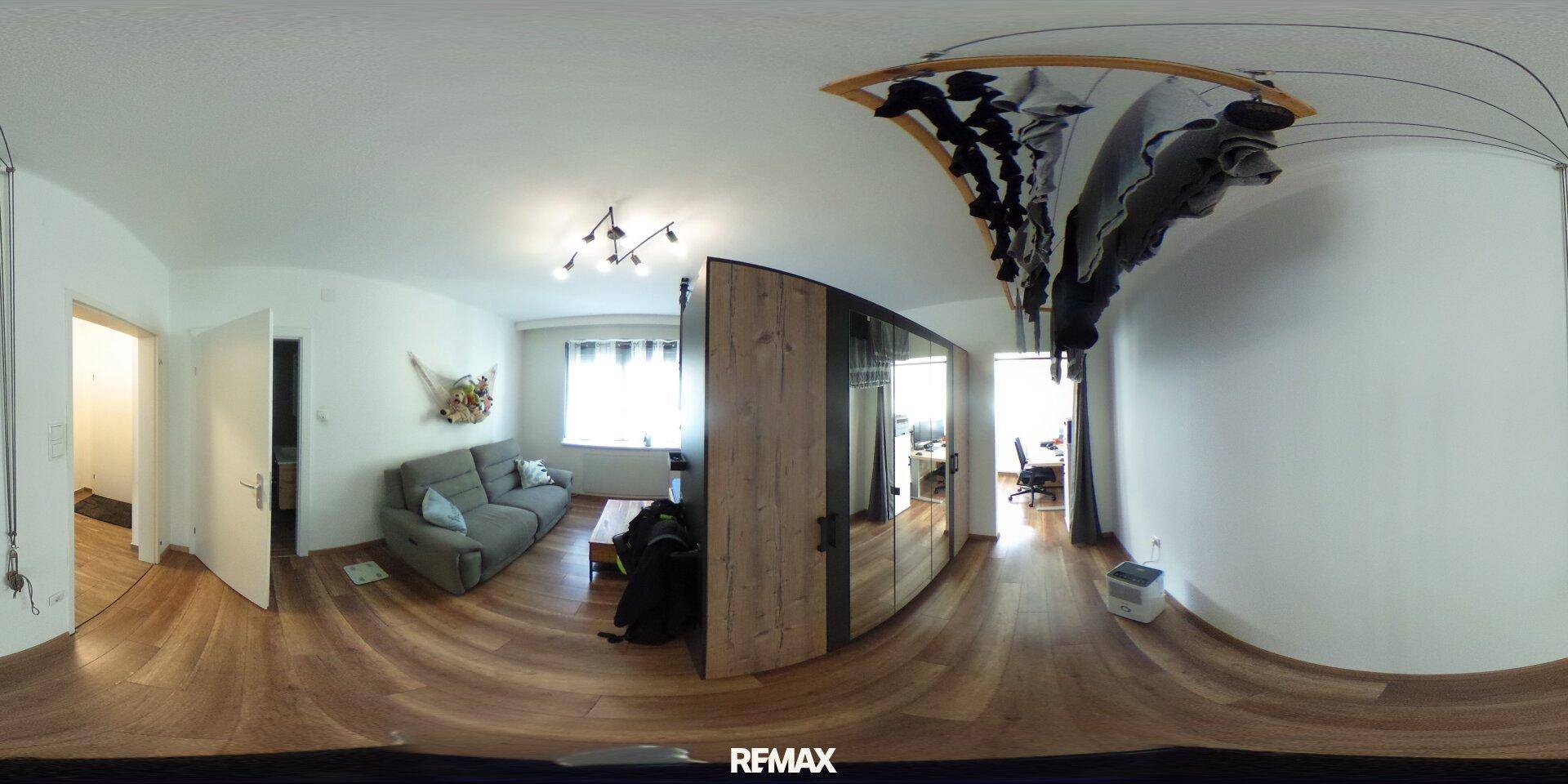 Wohnzimmer mit Sofa, Holzboden und großem Fenster, bietet viel Tageslicht.