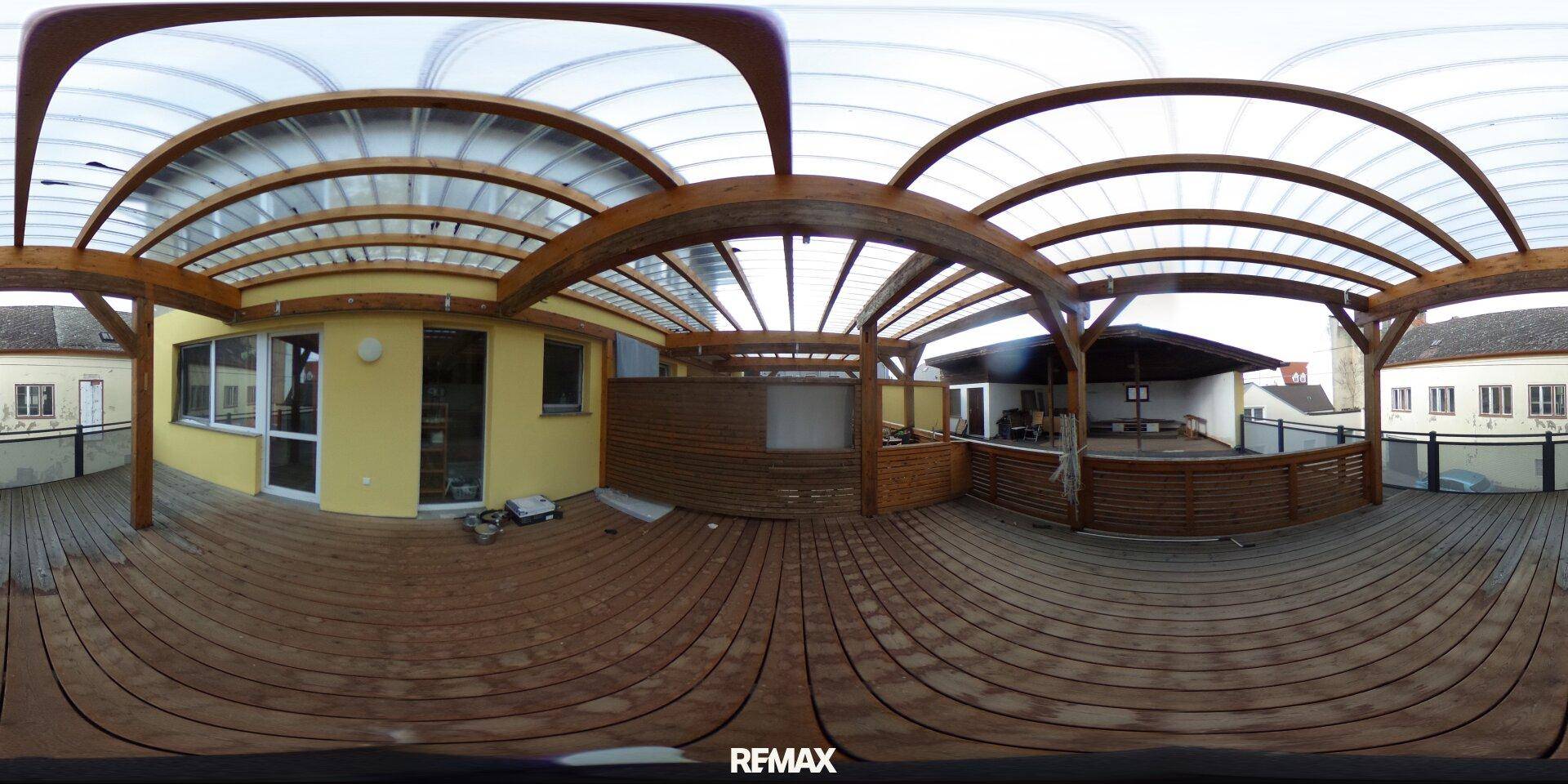 Große überdachte Holzterrasse mit Blick auf die Umgebung, ideal für Outdoor-Aktivitäten.