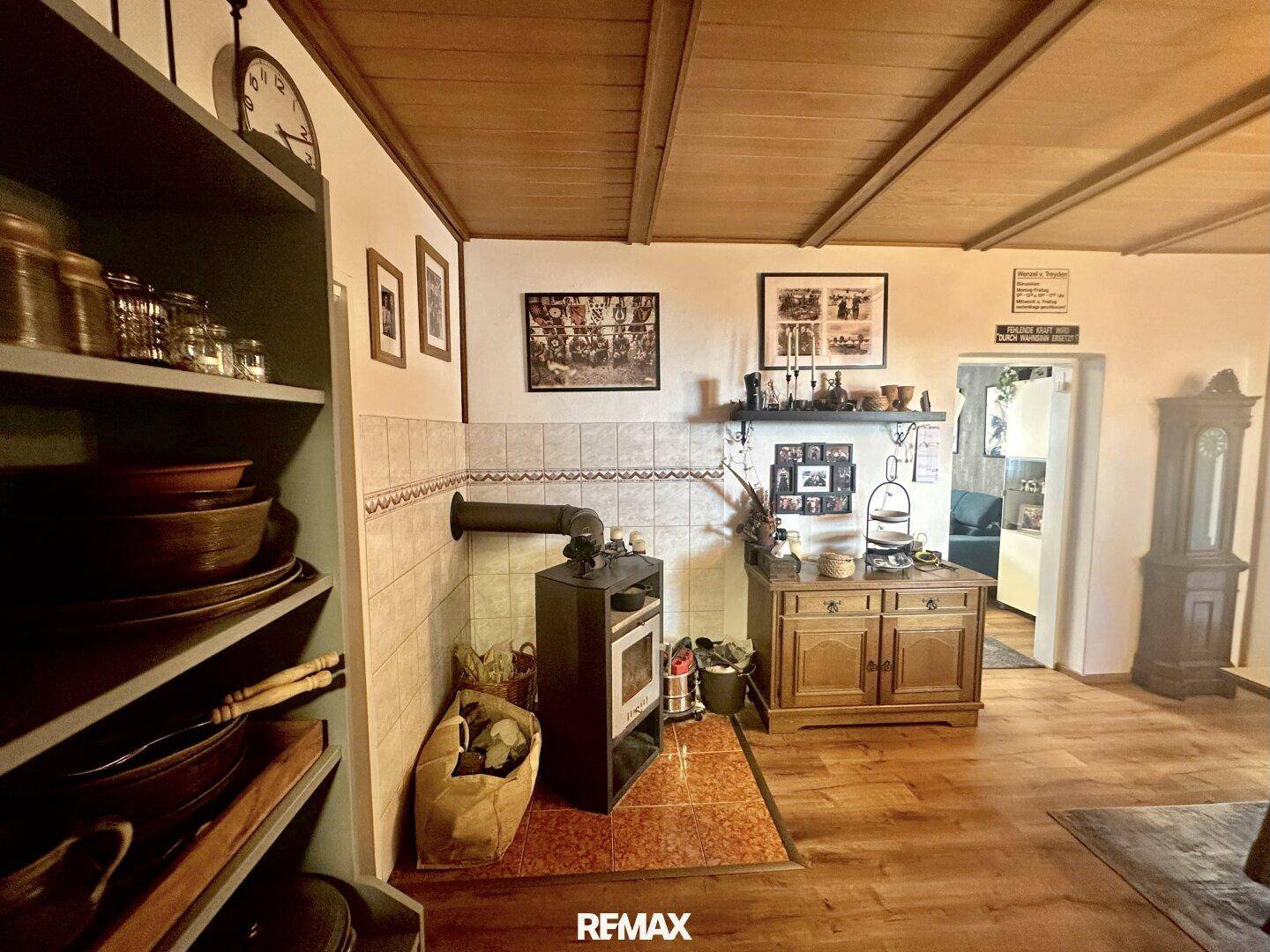 Rustikales Wohnzimmer mit Holzbalkendecke, Kaminofen und traditionellen Holzmöbeln.