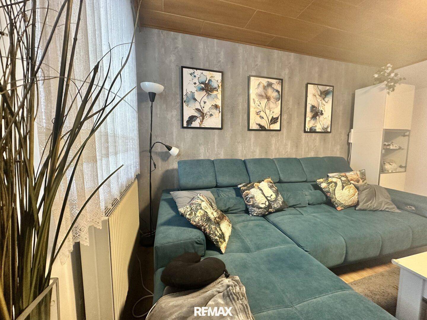 Gemütliches Wohnzimmer mit großem Ecksofa, strukturierter Tapete und Holzdecke.