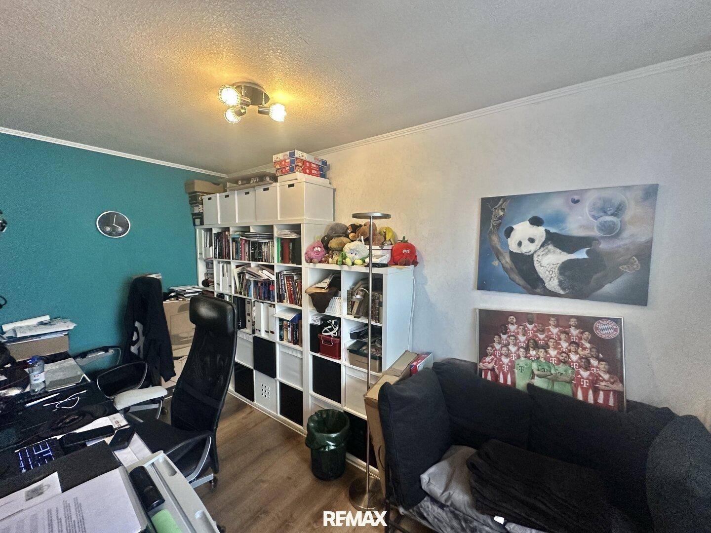 Arbeitszimmer mit Schreibtisch, Bücherregalen und einer kleinen Couch.