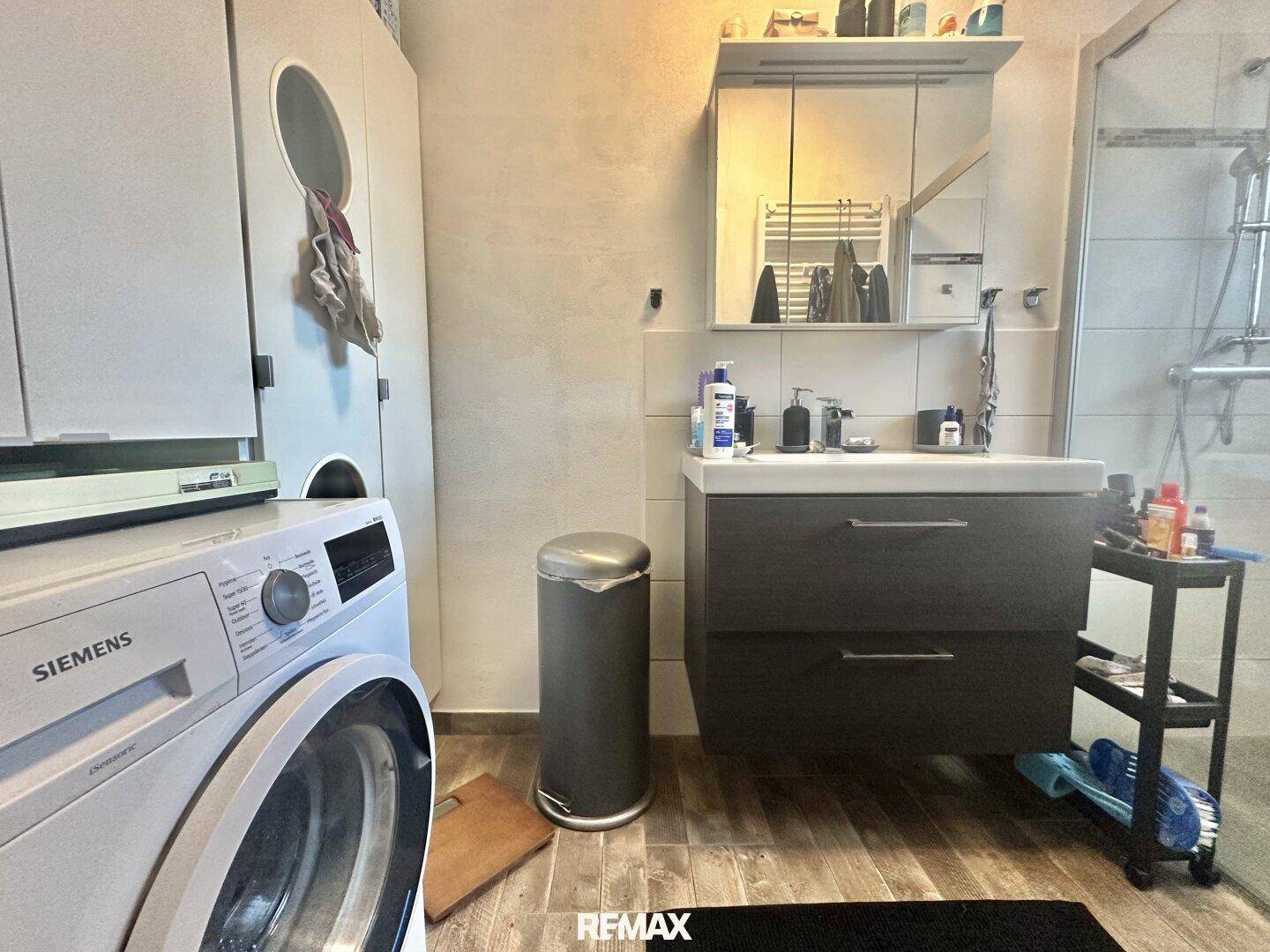 Badezimmer mit Waschbeckenunterschrank, Waschmaschine und Trockner.