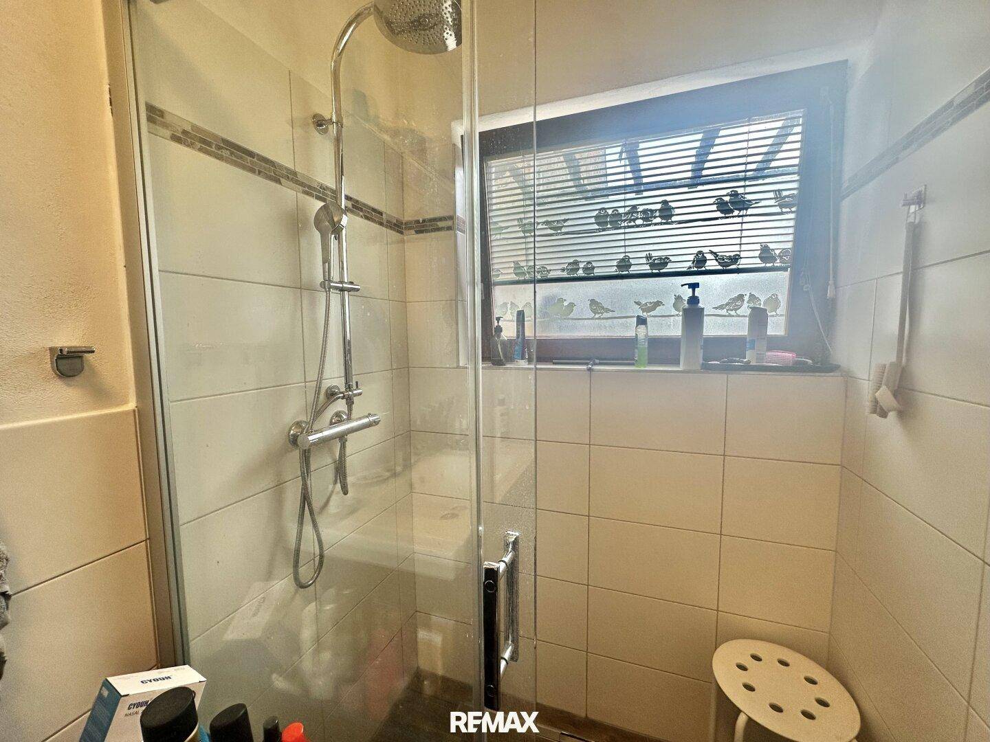 Badezimmer mit begehbarer Dusche und hell gefliesten Wänden.