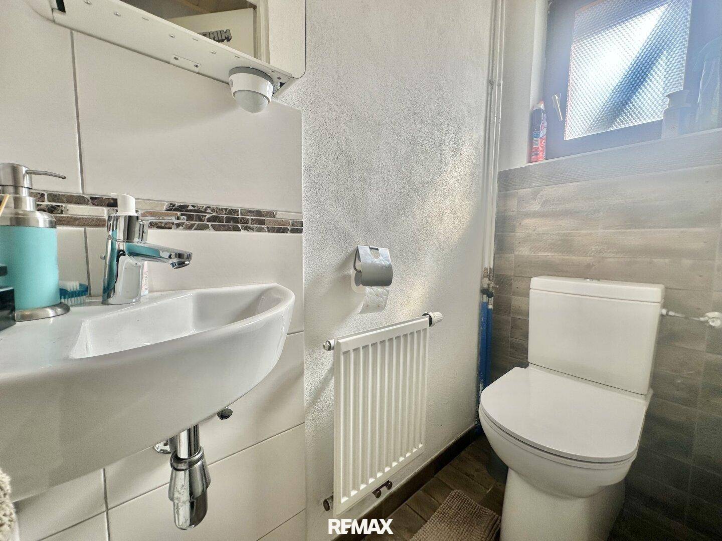 Kleines Gäste-WC mit Toilette, Waschbecken und Heizkörper.