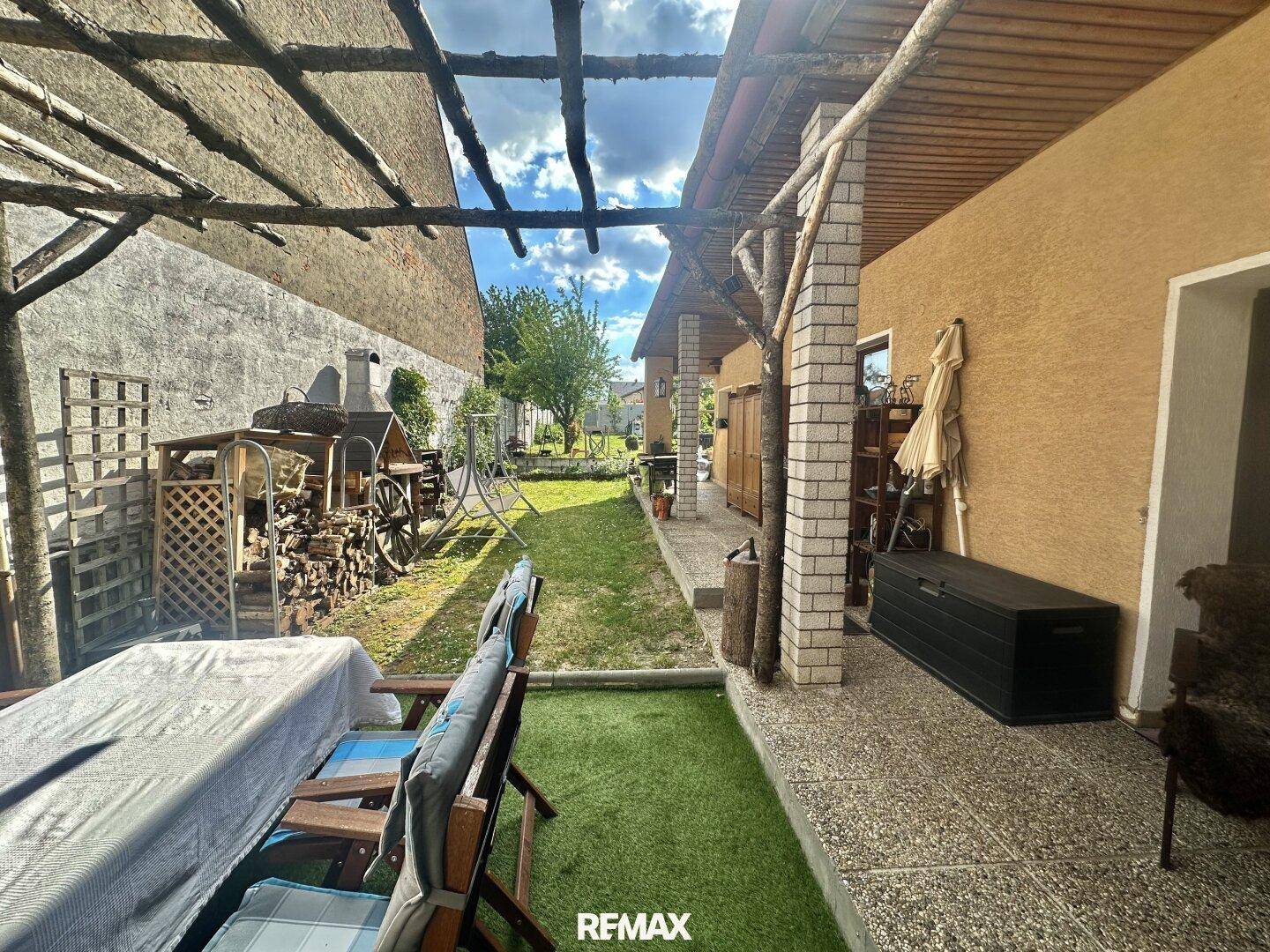 Gemütlicher Außenbereich mit überdachter Terrasse, Sitzgelegenheiten und Blick in den Garten.