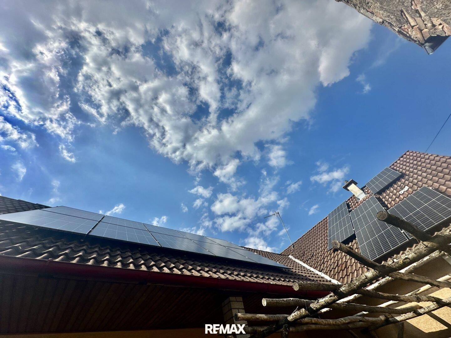 Dach eines Gebäudes mit installierten Photovoltaikmodulen unter blauem Himmel.