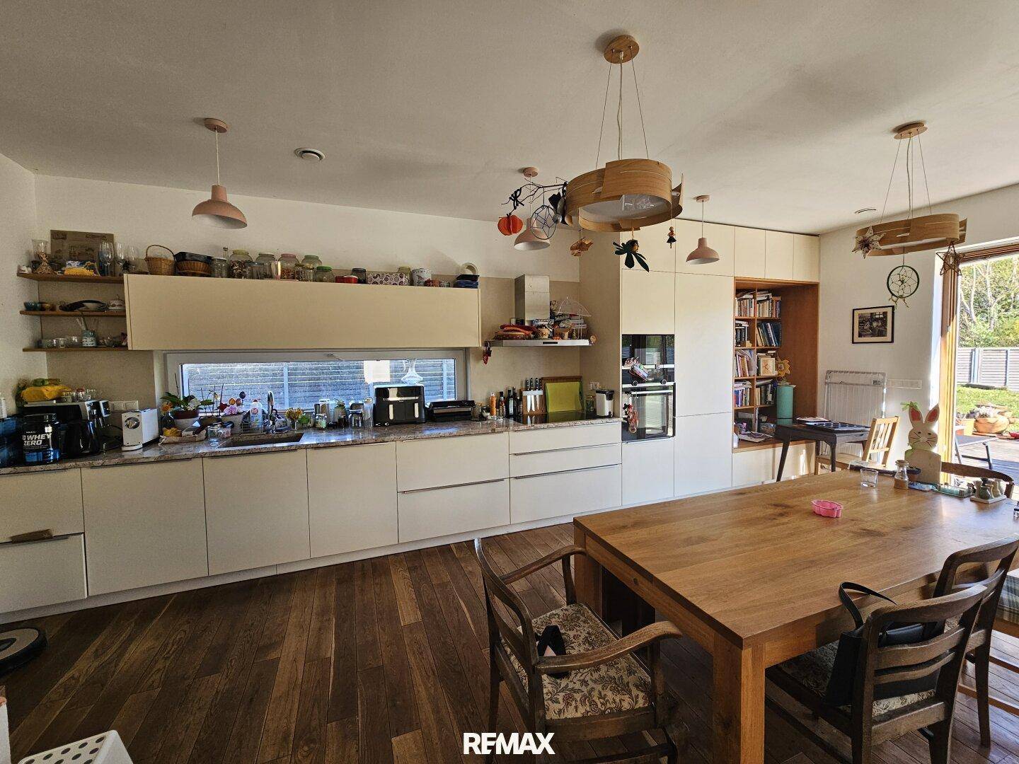 Helle, moderne Einbauküche mit Holz-Esstisch und viel Stauraum, offen zum Wohnbereich.