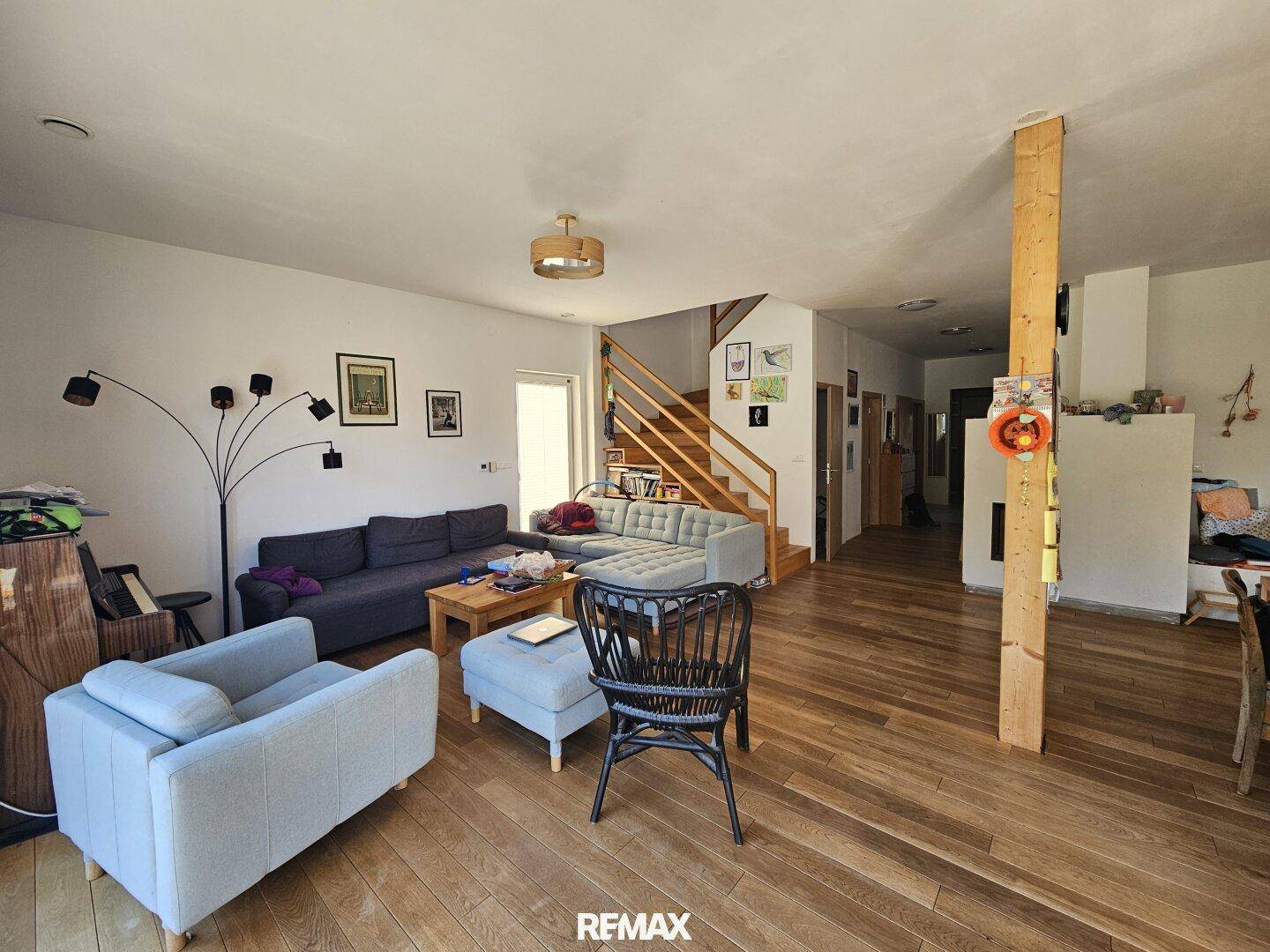 Gemütlicher Wohnbereich mit großem Sofa, Holzboden und Treppe zum Obergeschoss.