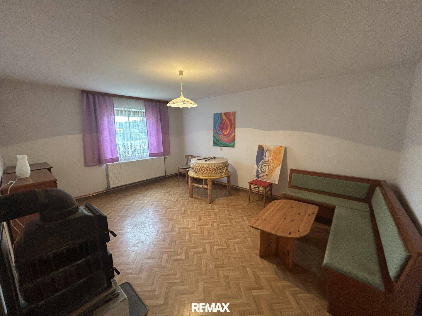 Wohnzimmer mit Holzparkett, Kaminofen und gemütlicher Sitzecke, ideal für entspannte Abende.