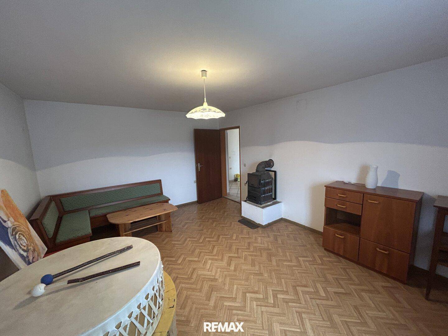 Wohnzimmer mit Holzparkett, Kaminofen und gemütlicher Sitzecke, ideal für entspannte Abende.