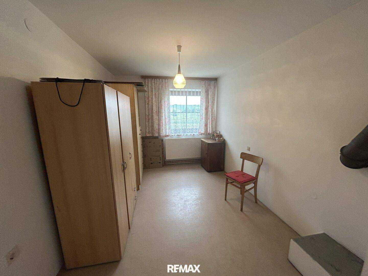 Schlafzimmer mit Laminatboden, Kleiderschränken und Blick auf die grüne Umgebung.