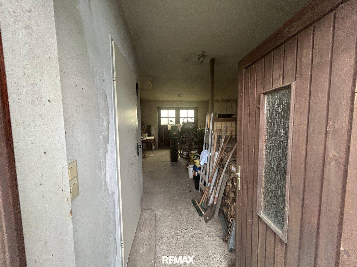 Eingangsbereich zur Garage mit Holztür und Blick in den Arbeitsbereich.