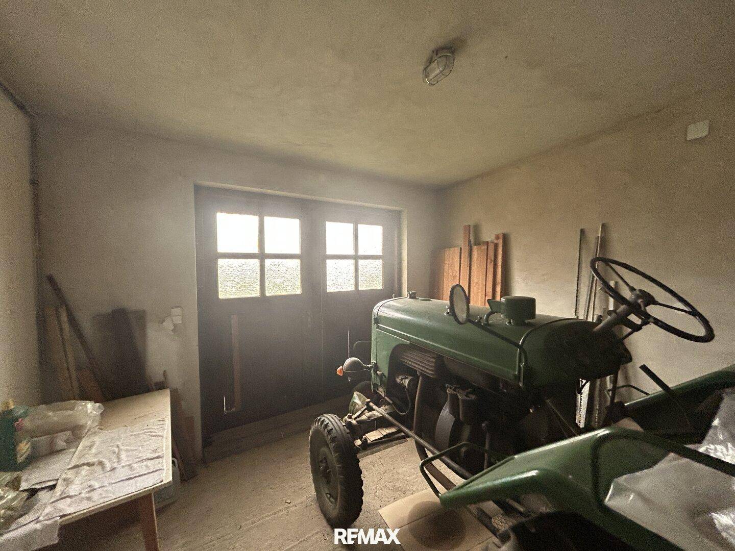 Geräumige Garage mit Betonboden und Doppeltüren, bietet viel Platz für Fahrzeuge.
