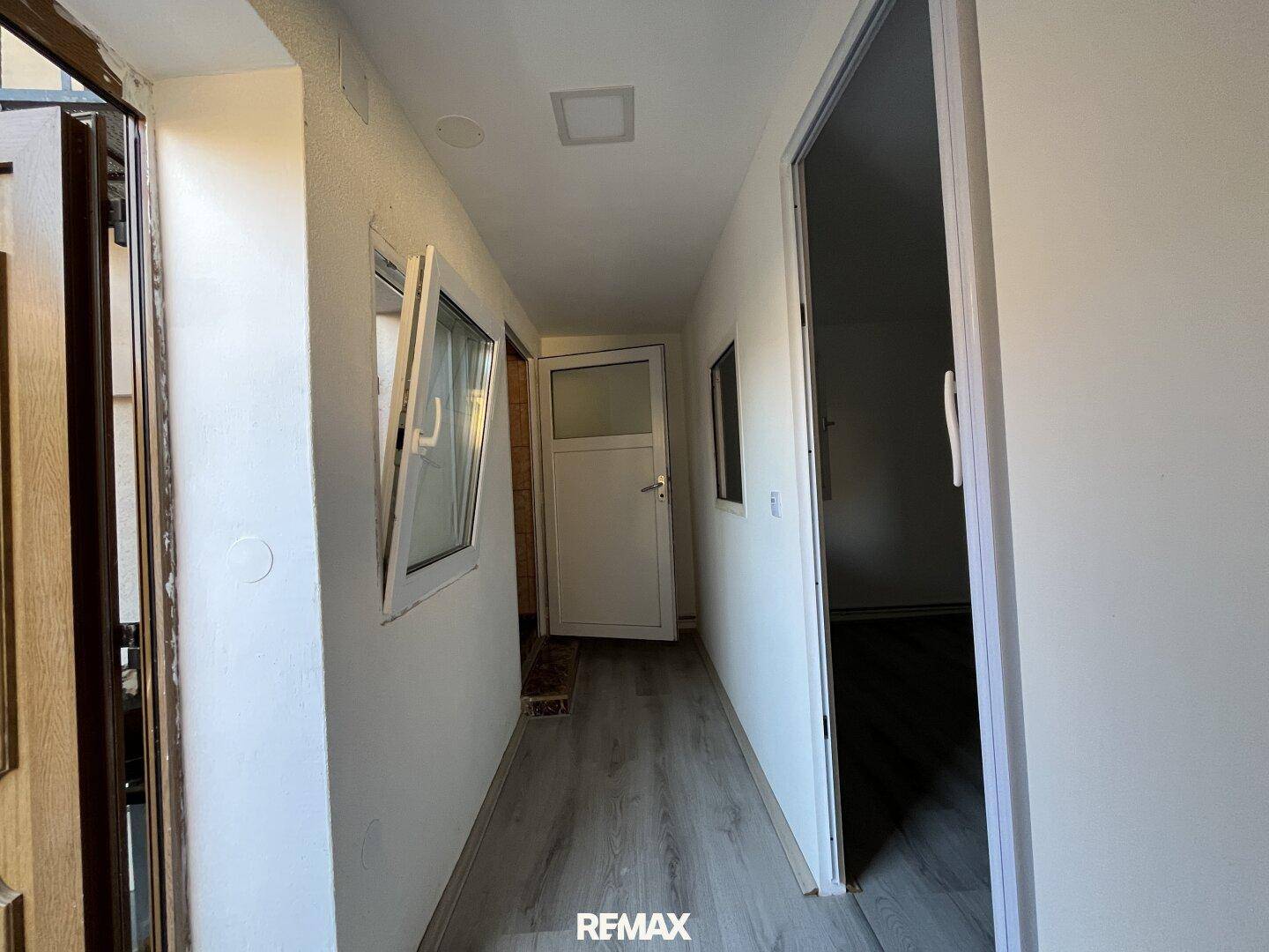 Heller Flur mit Laminatboden und Fenstern, die für natürliches Licht sorgen.