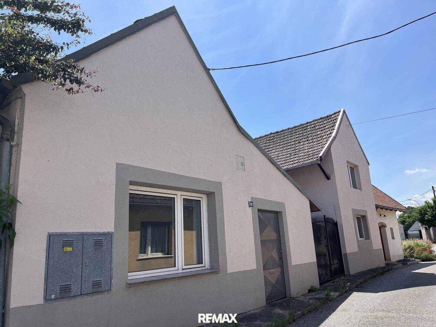 Ansicht eines Wohnhauses mit heller Fassade, Satteldach und Fenstern zur Straße hin.