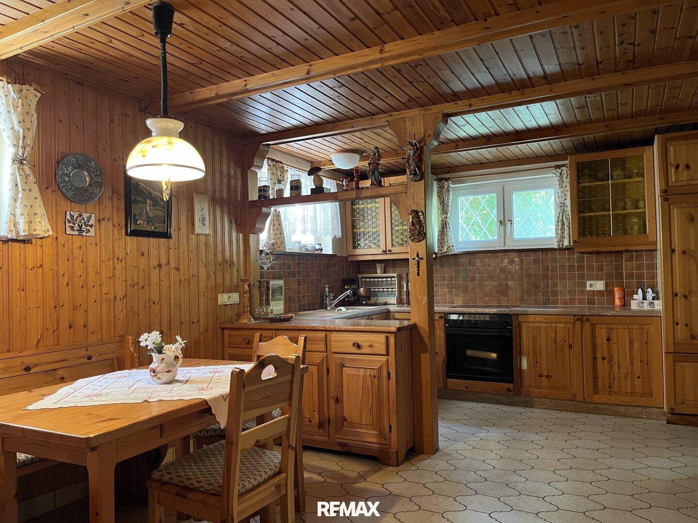 Rustikale Wohnküche mit Holztäfelung, Holzdecke und Esstisch, gemütlich und traditionell.